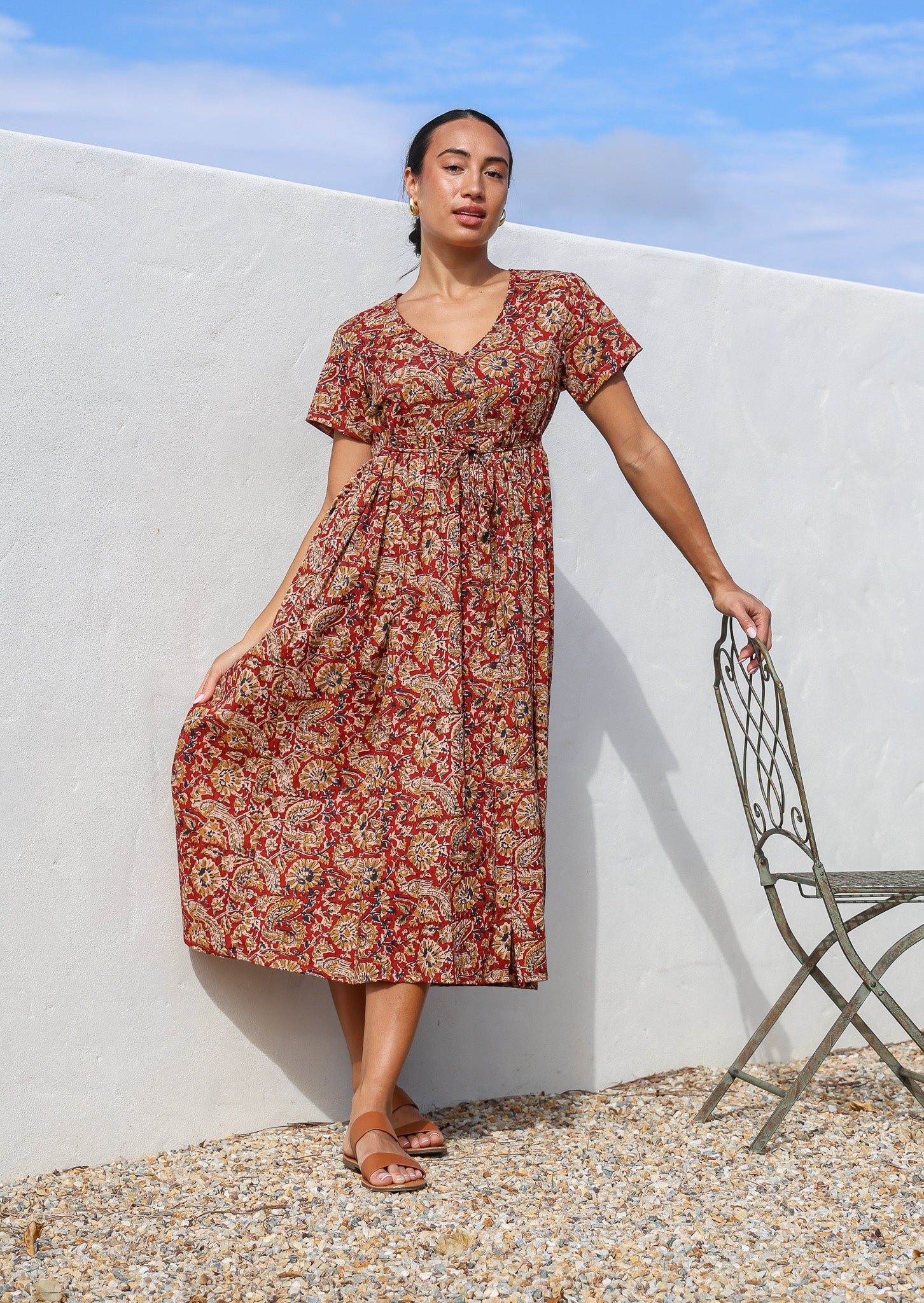 Woman wears 100% cotton button through relaxed fit dress with short sleeves and V-neckline in floral print on a red base