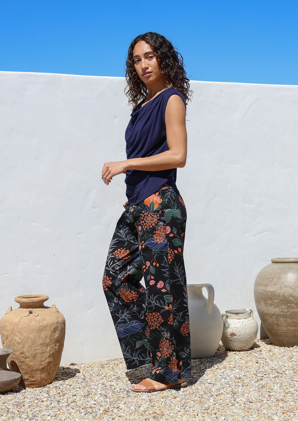 Model poses in black floral cotton pants with side zipper, pockets and wide leg fit