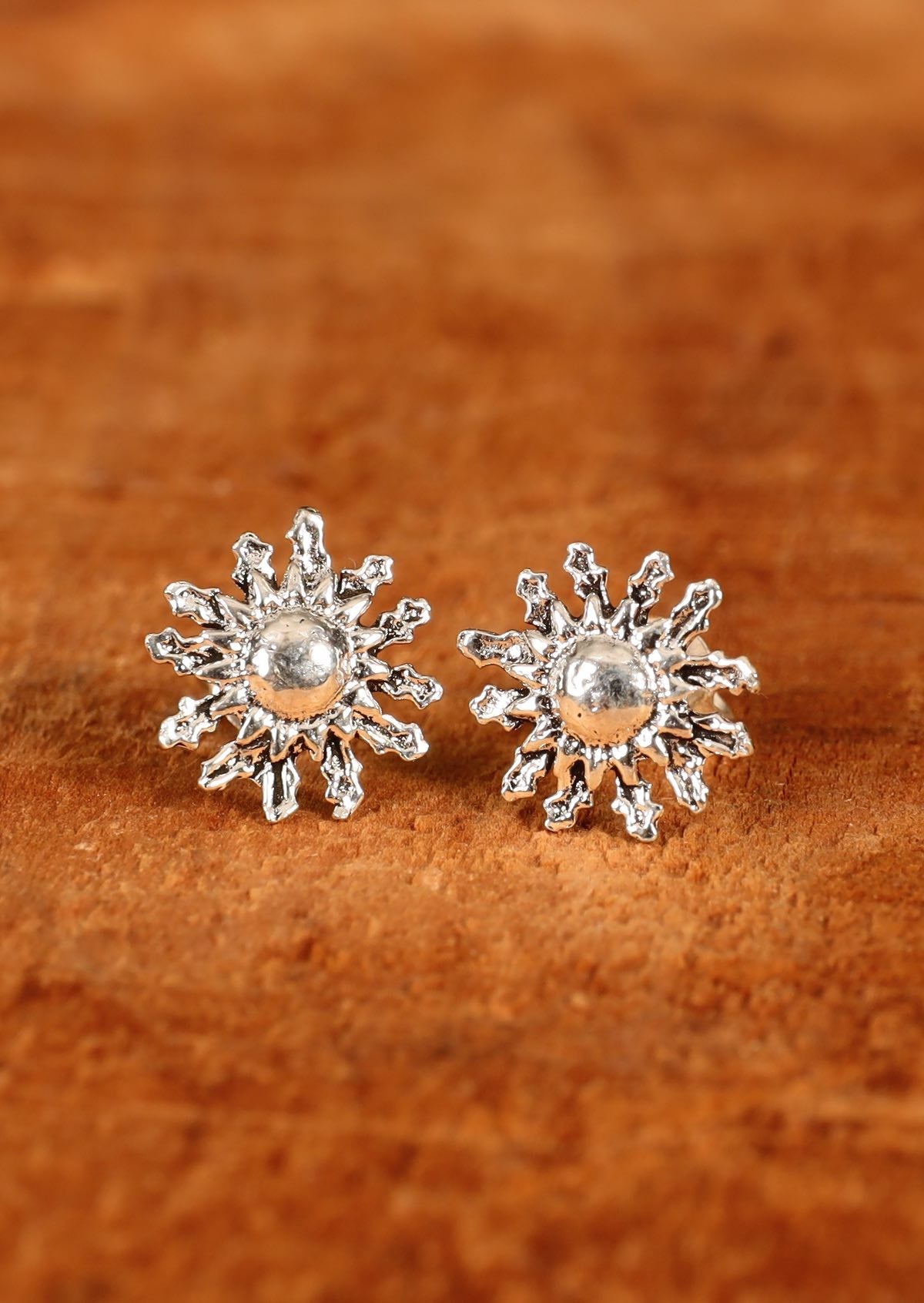 92.5% silver floral earrings sitting on wood for display