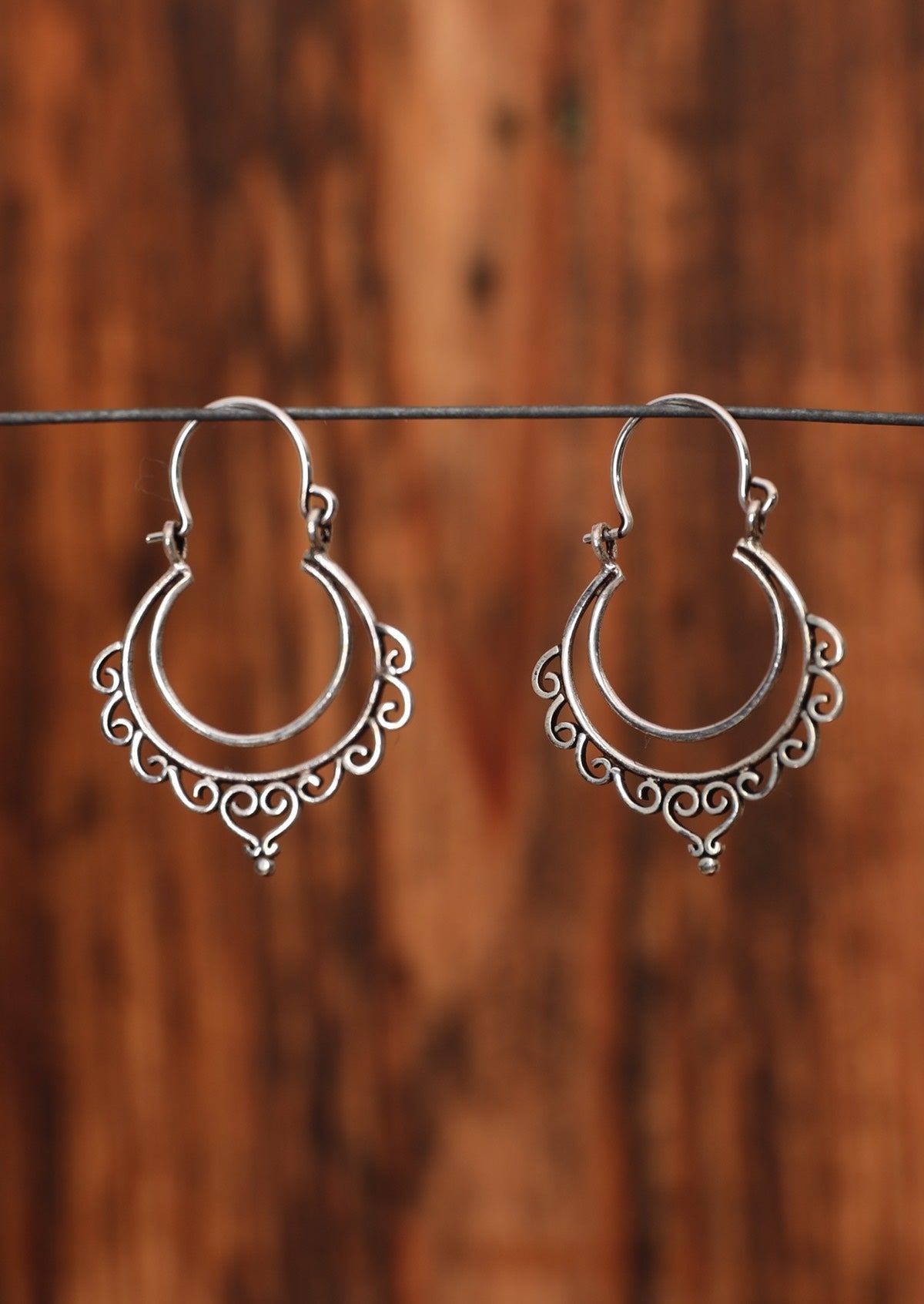 92.5% silver boho style earrings with curves sitting on a wire for display.