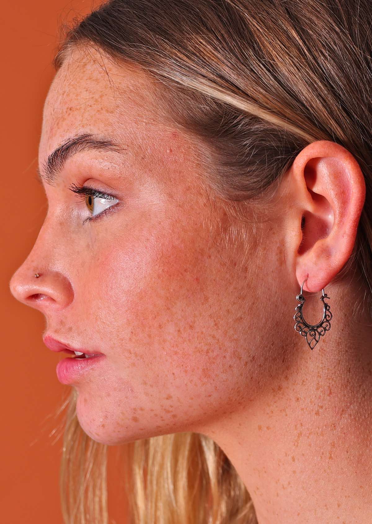 Woman wears silver wire spiral detailed hoop earring
