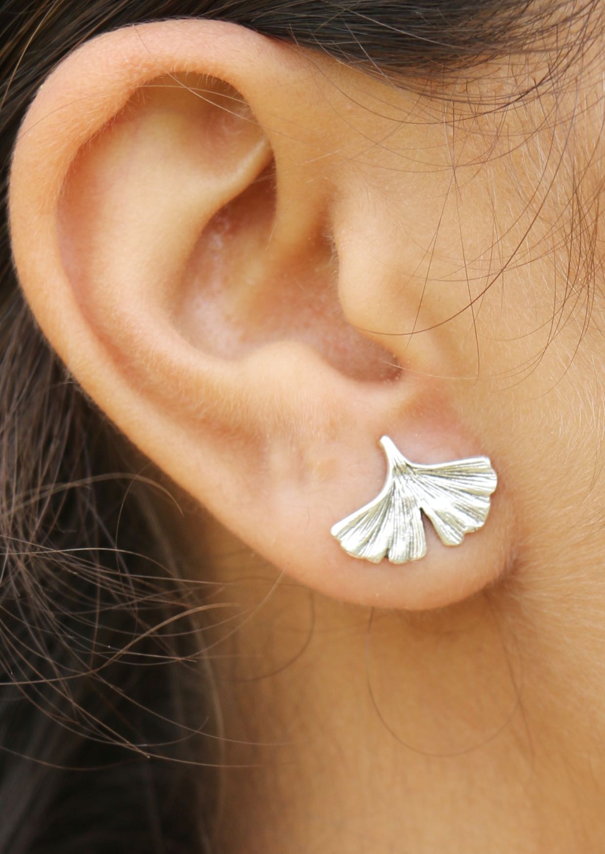Close up of an ear with a sterling silver Ginkgo leaf-shaped studs
