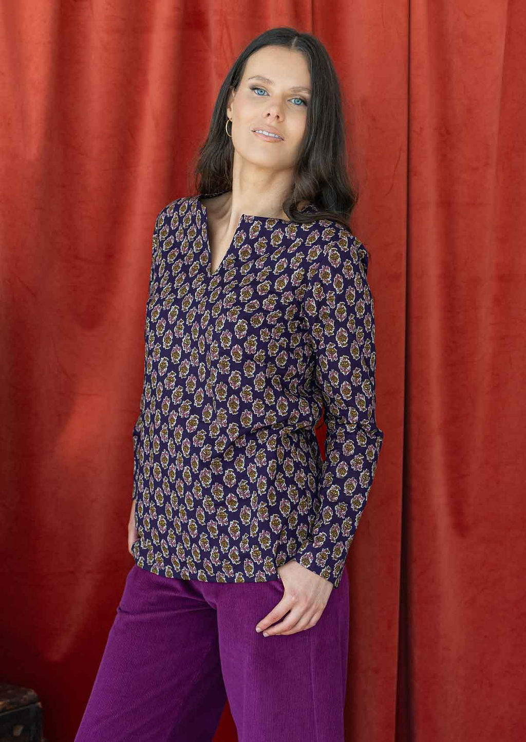 Model wears long sleeve cotton shirt top with round neckline and v cutout. Paired with plum corduroy pants.