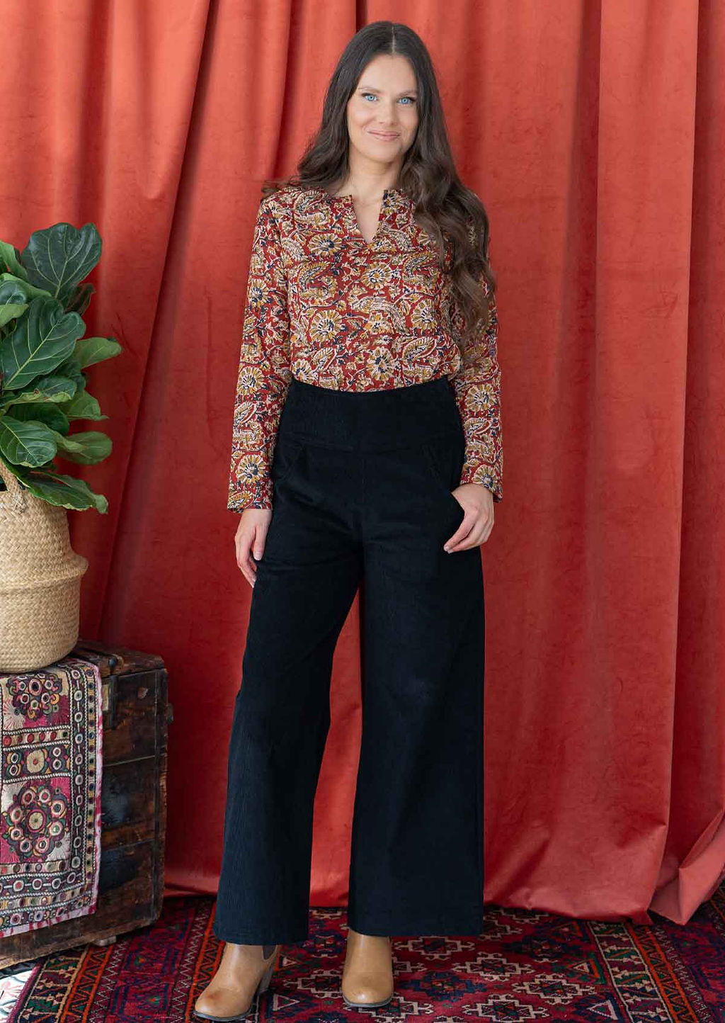 Woman wears cotton long sleeve top tucked in black corduroy pants.