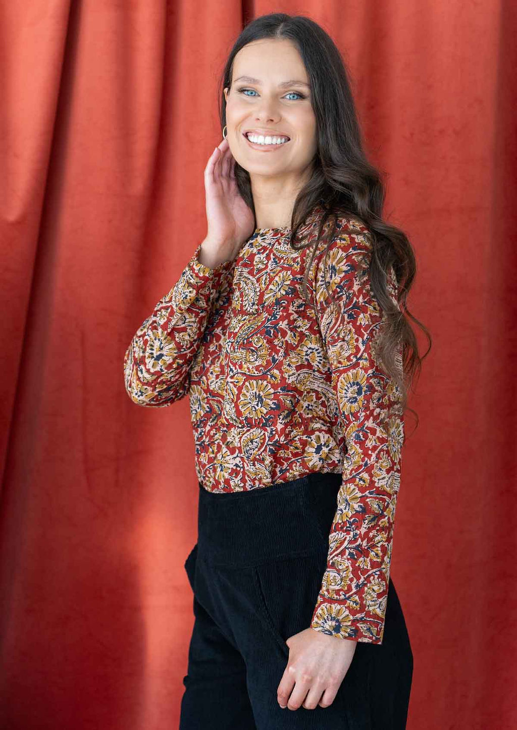 Model posing in a cotton long sleeve top in red based Indian floral print.