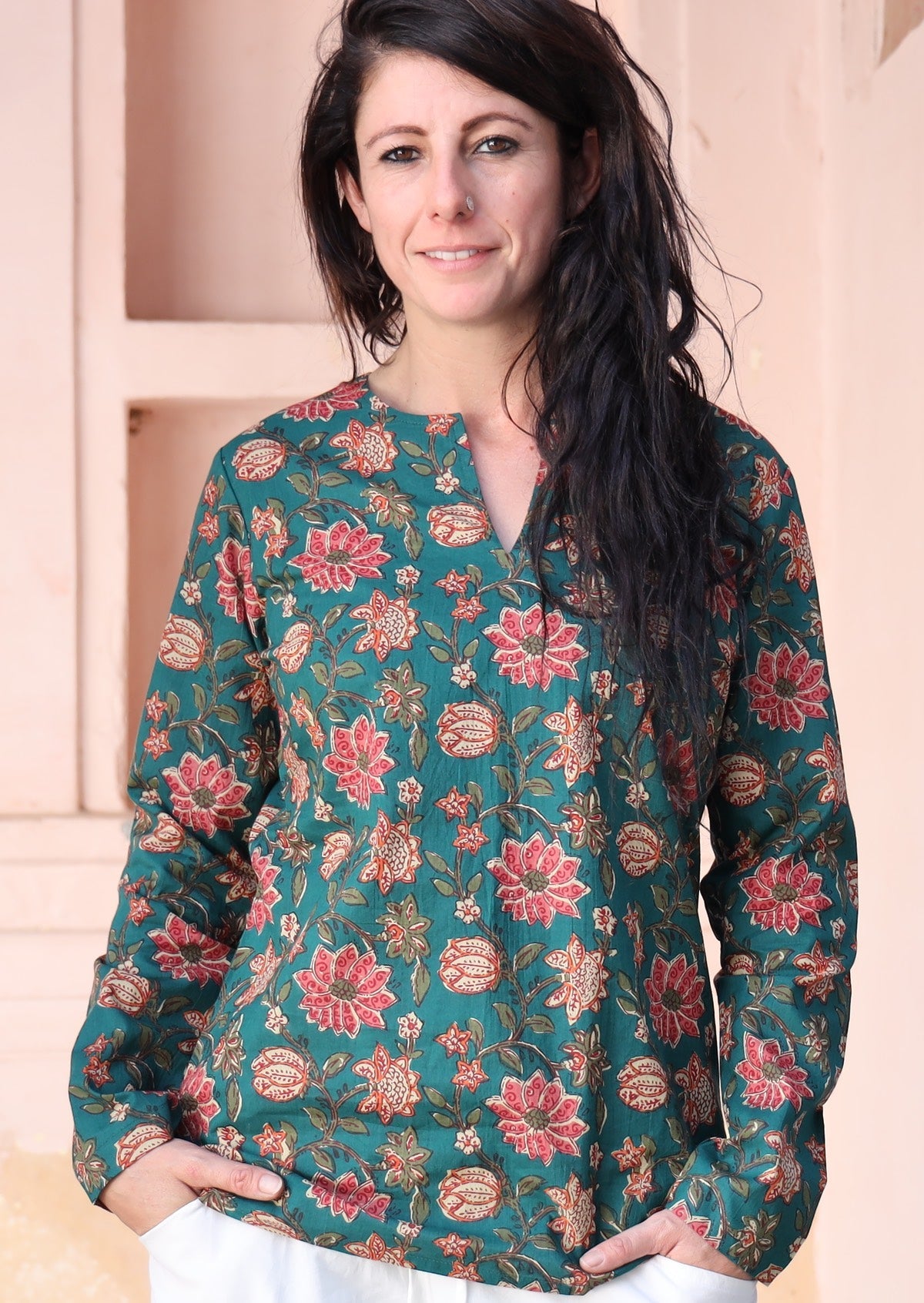 Woman wears cotton long sleeve top with V-cutout in neckline, in floral print on a green base