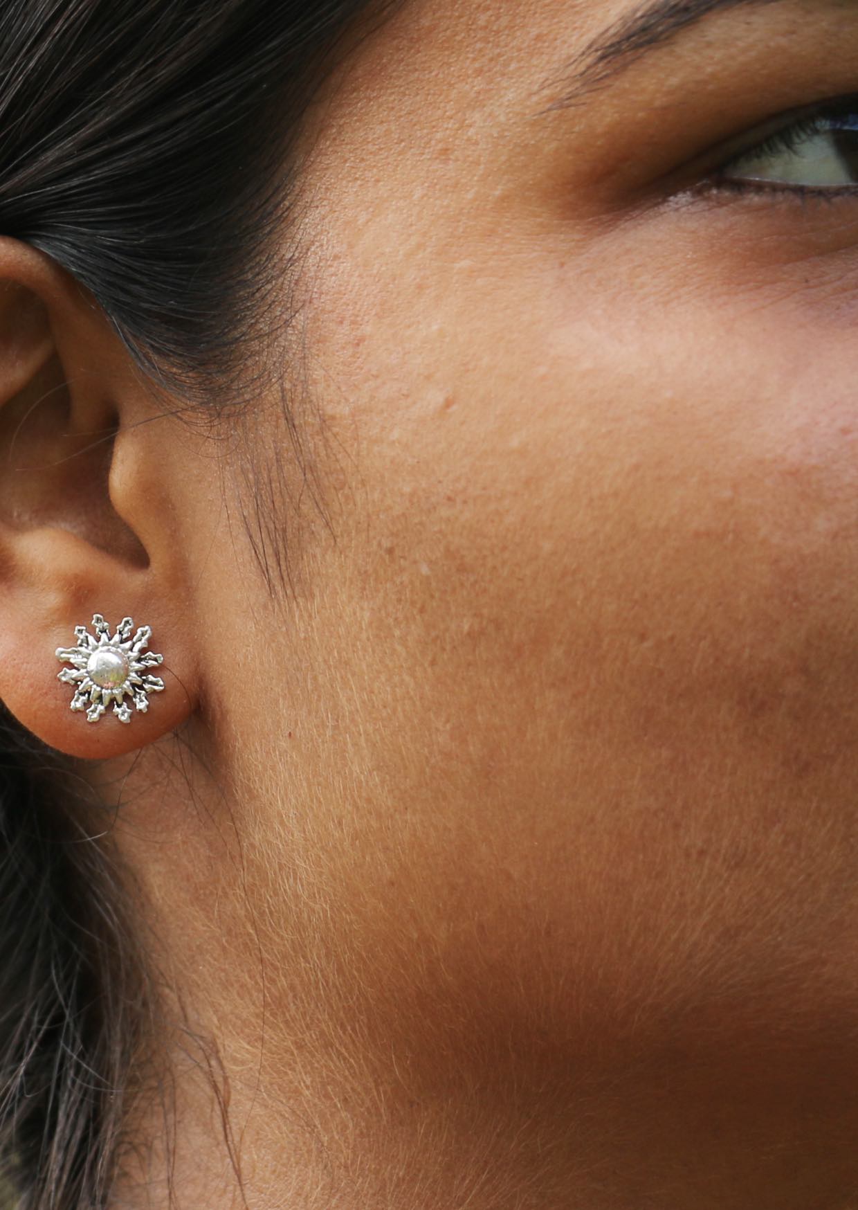 Close up of a person wearing a sun blossom silver studs with secure butterfly backs