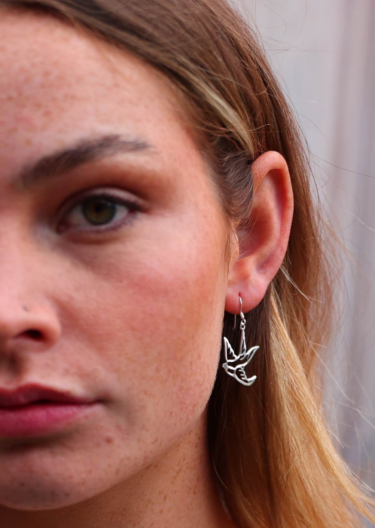 Woman wearing dangly silver bird earrings