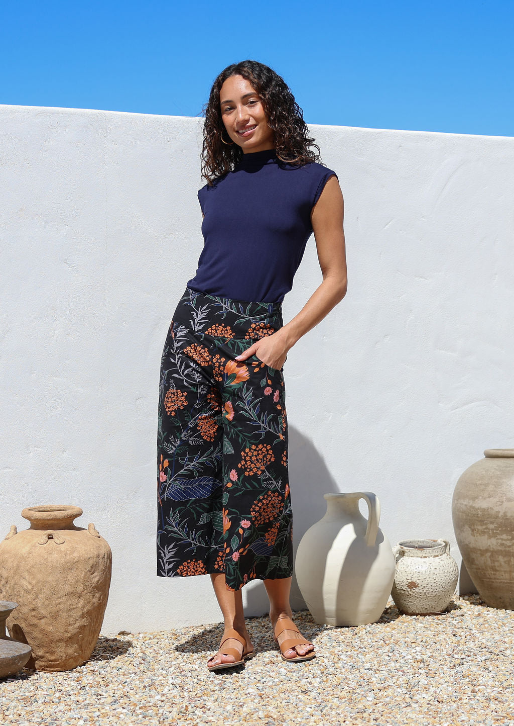 Woman wearing a navy basic rayon top and black botanical print wide leg 3/4 cotton pants with side zipper and pockets