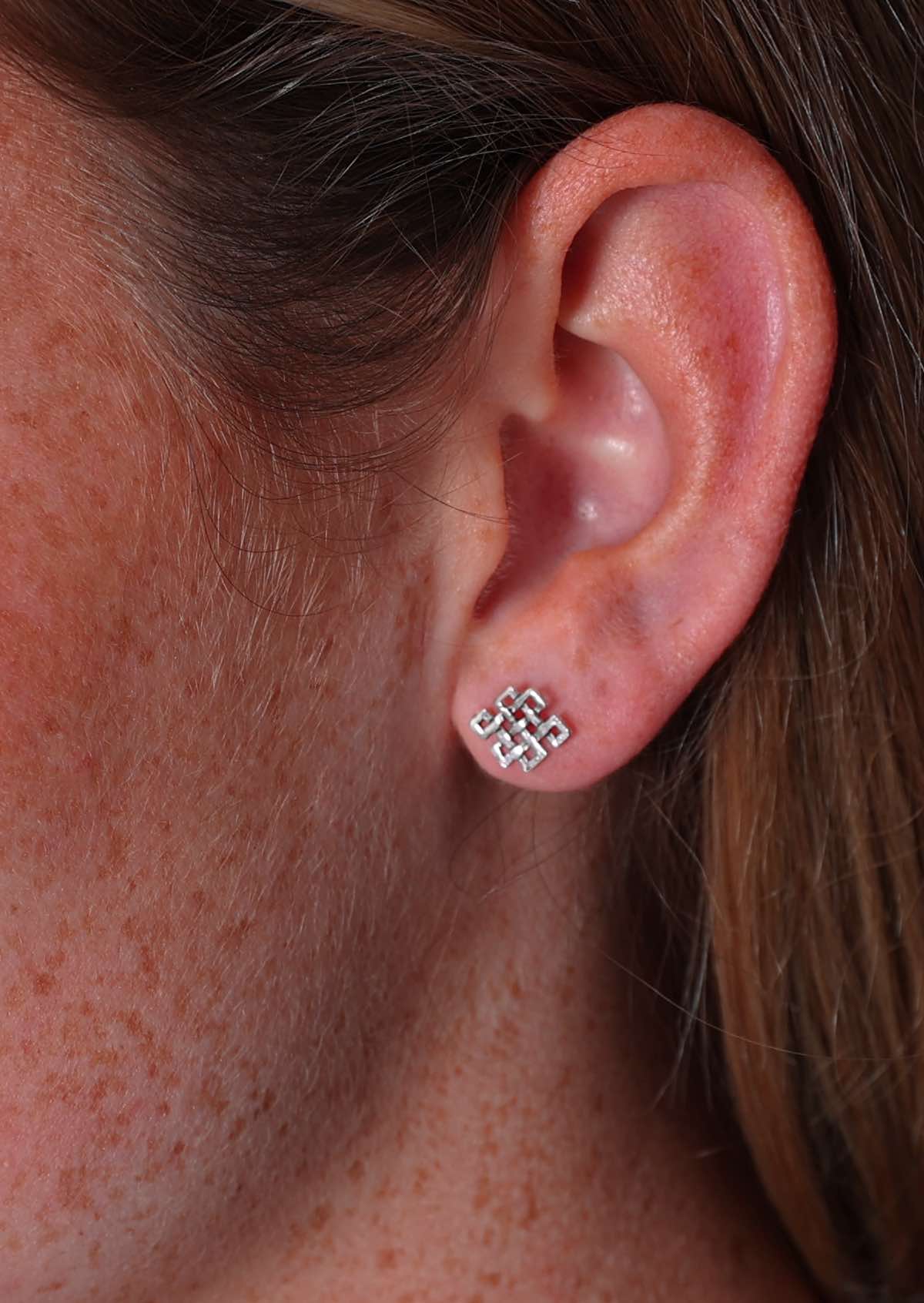 Close up of Tibetan Endless Knot sterling silver stud earring