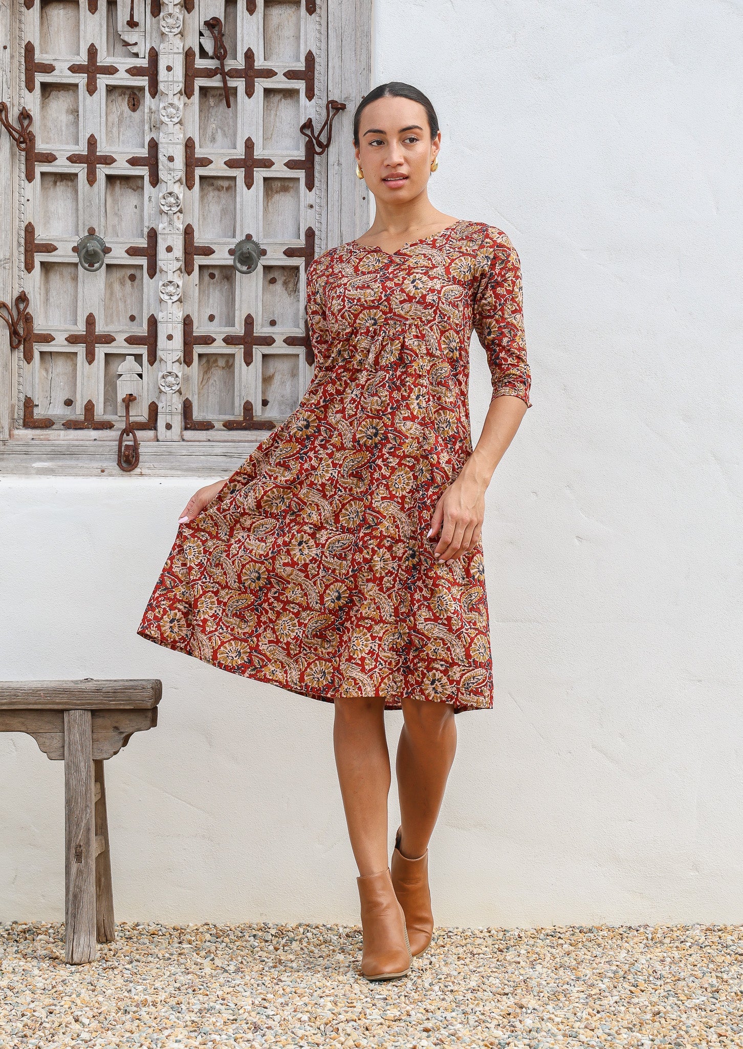 Model standing in 3/4 sleeves floral printed cotton dress with round neckline, pockets and pin tucks at the waist.