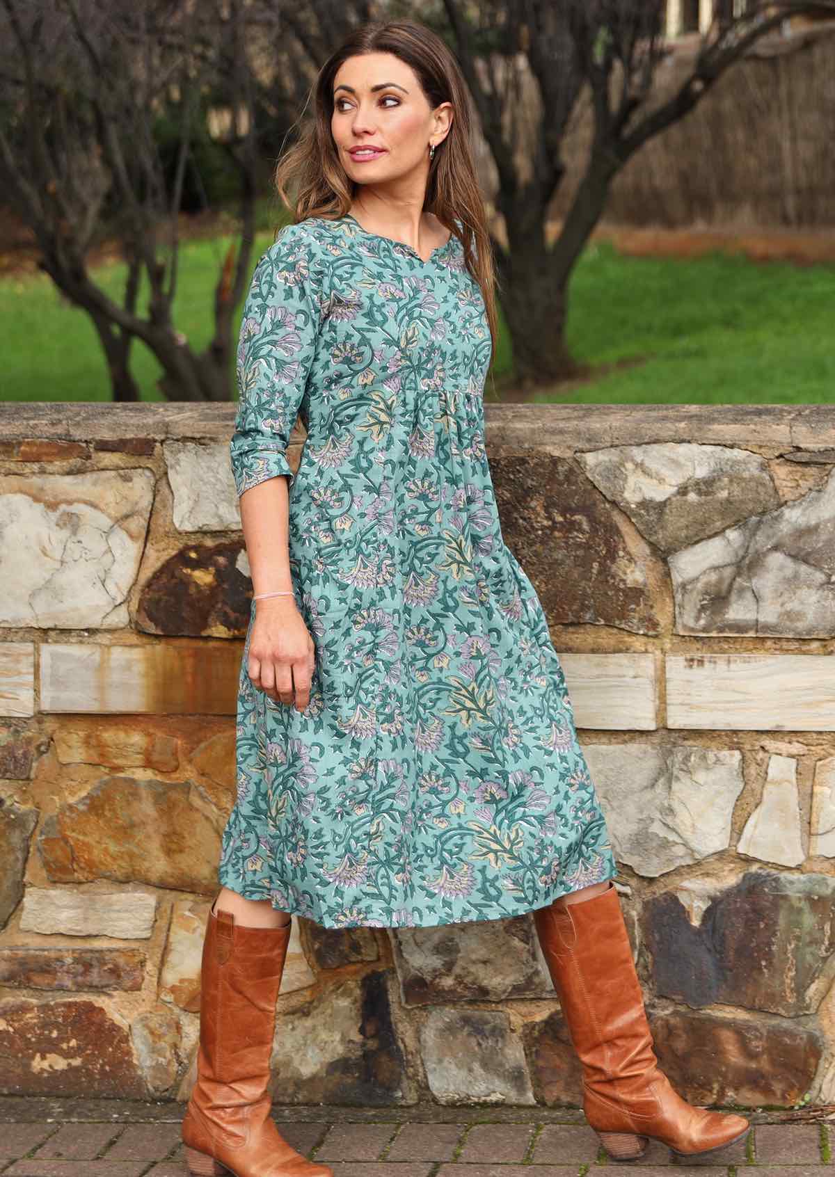 Model wears below knee length cotton dress with 3/4 sleeves, pockets and empire waist.