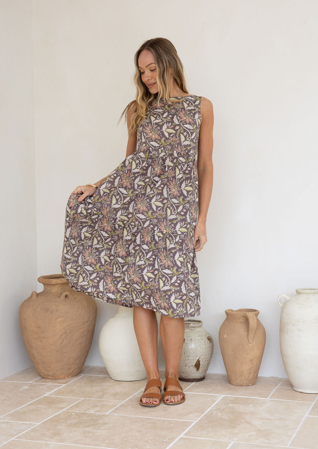 Woman flaunts 100 percent cotton relaxed fit sleeveless dress with high round neckline, pockets and tiered style.