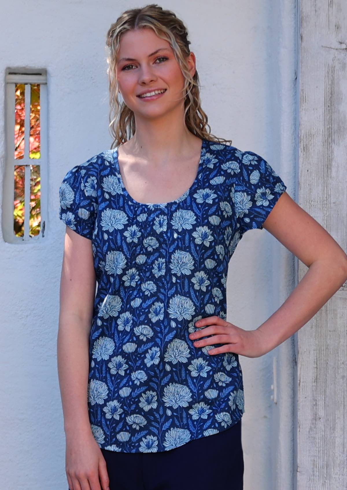 Model with hand on hip wearing 100 percent cotton navy floral blouse with scoop neck
