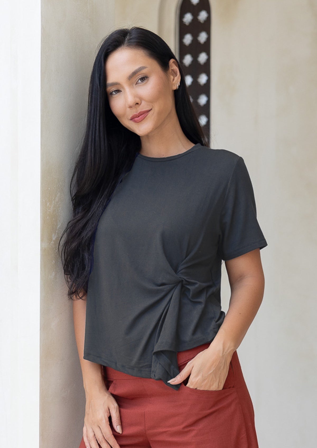 Woman wears dark grey rayon t-shirt with short sleeves and knot detail in the front