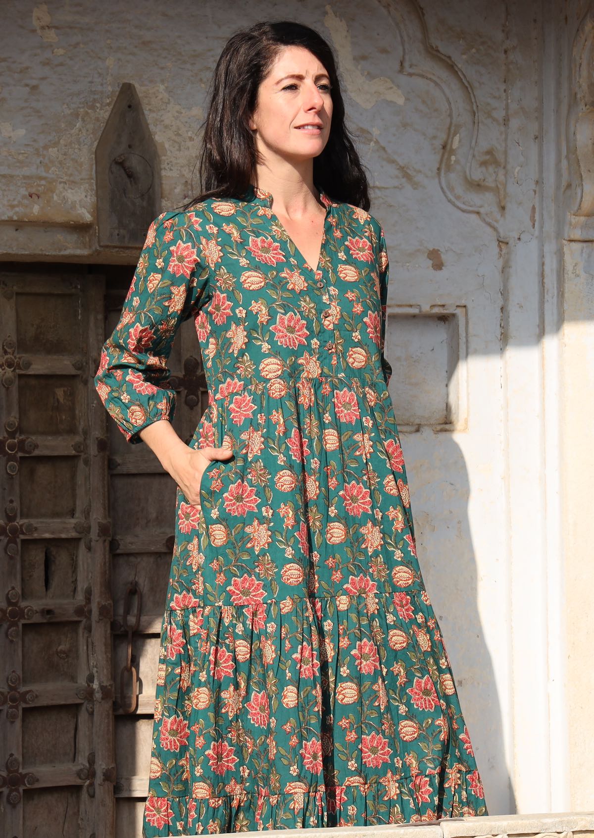 Model standing in sunshine wears a beautiful green cotton maxi dress with pockets, mandarin collar and 3/4 sleeves.