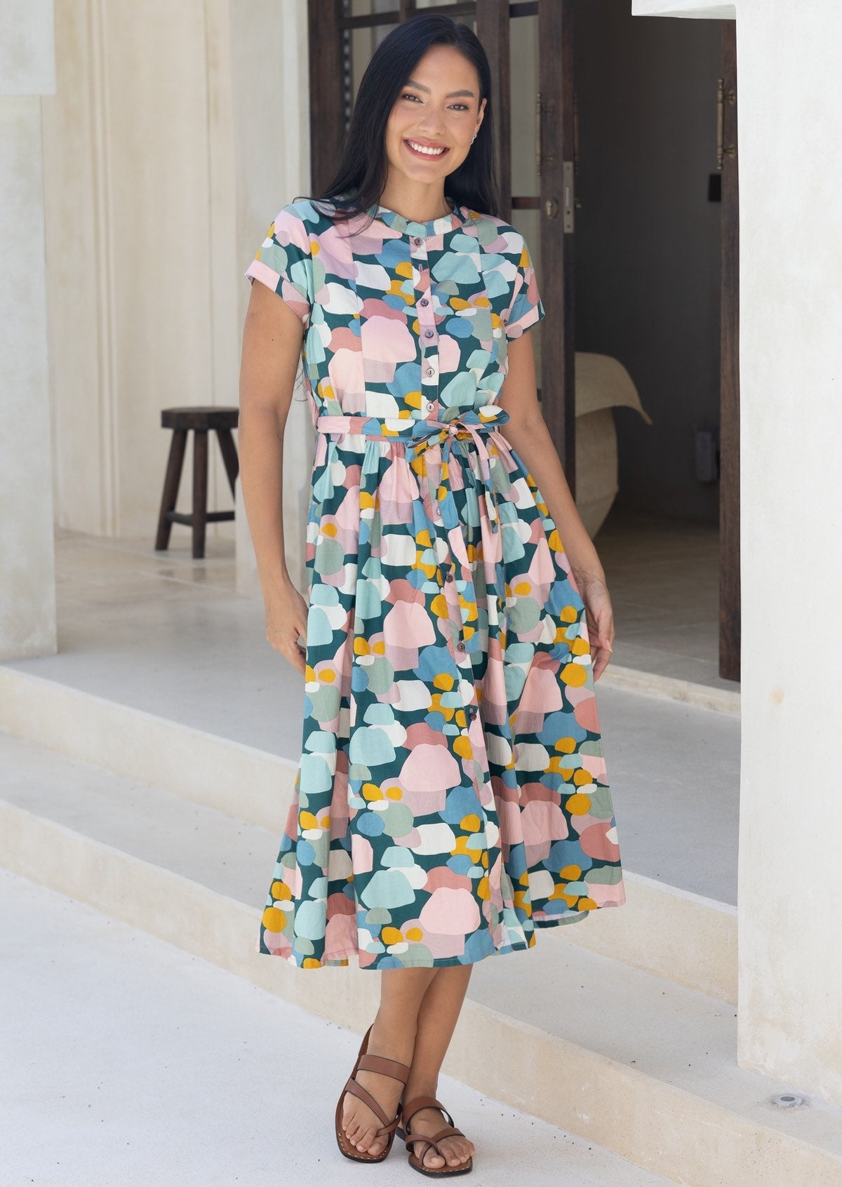 Woman standing in cotton 50's style button through dress with mandarin collar, in pastel colours