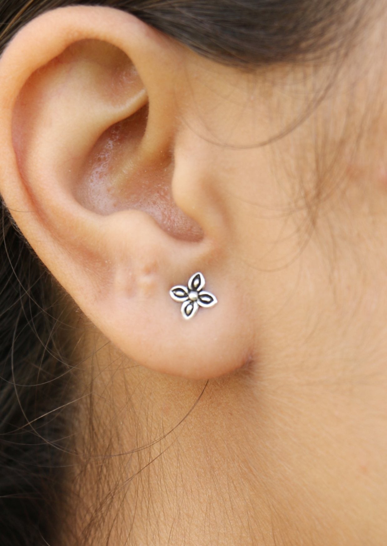 A woman is wearing Zieria Silver Studs, featuring a delicate four petal leaf design with secure butterfly backs