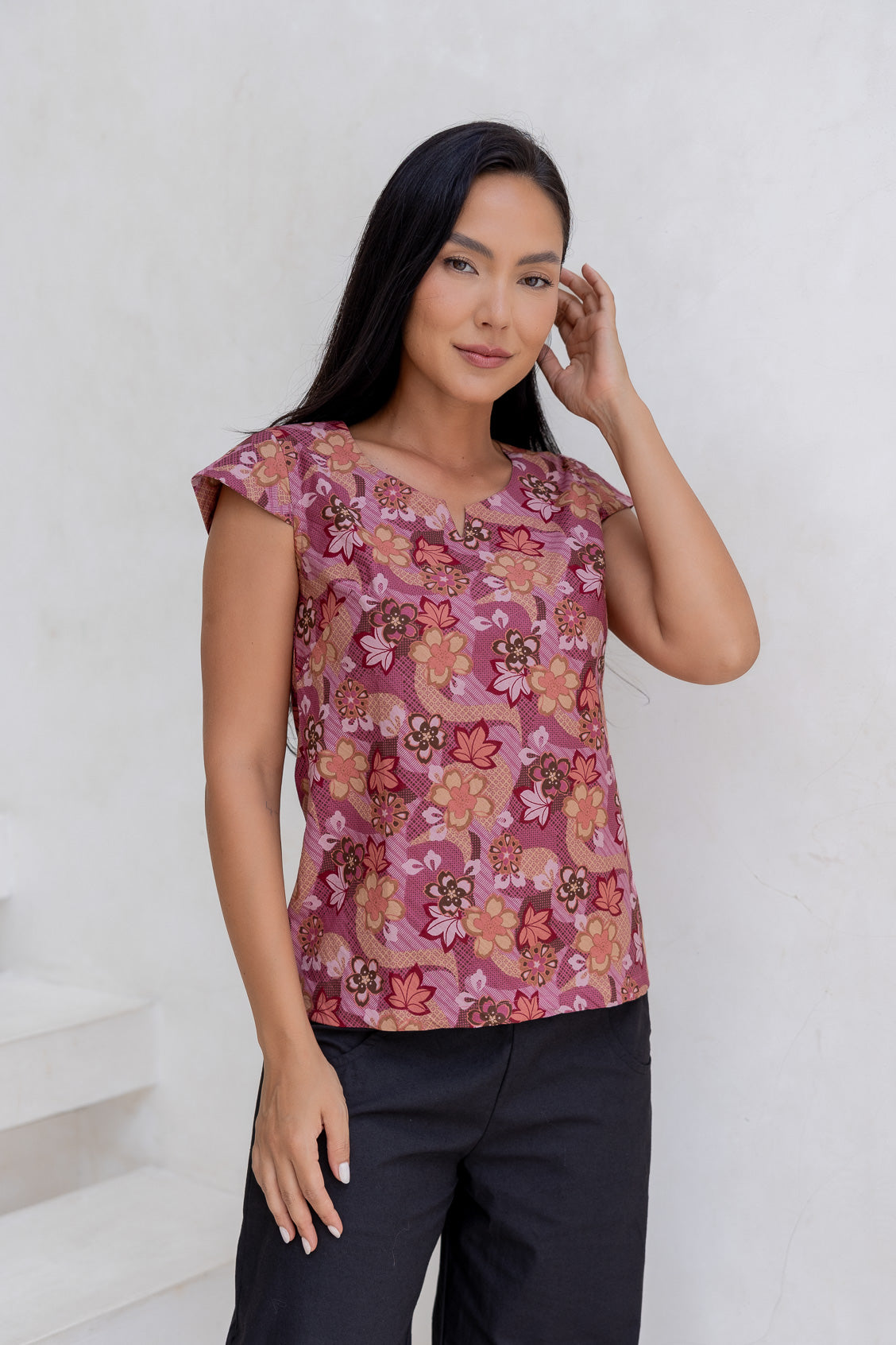 A woman poses in a cap-sleeved cotton tailored top with a Japanese style floral print