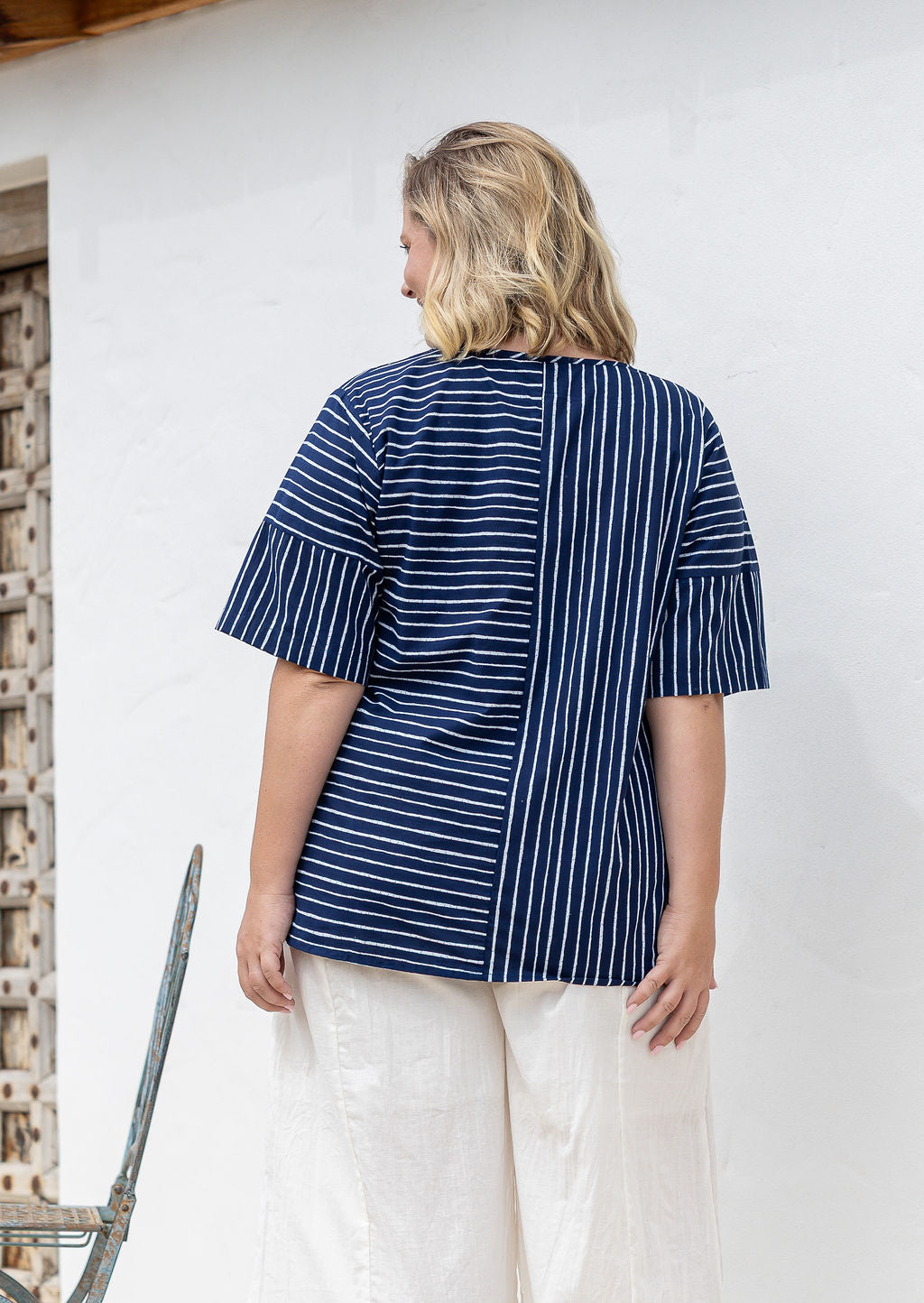 Woman stands backwards wears a navy and white striped 100% cotton relaxed fit top