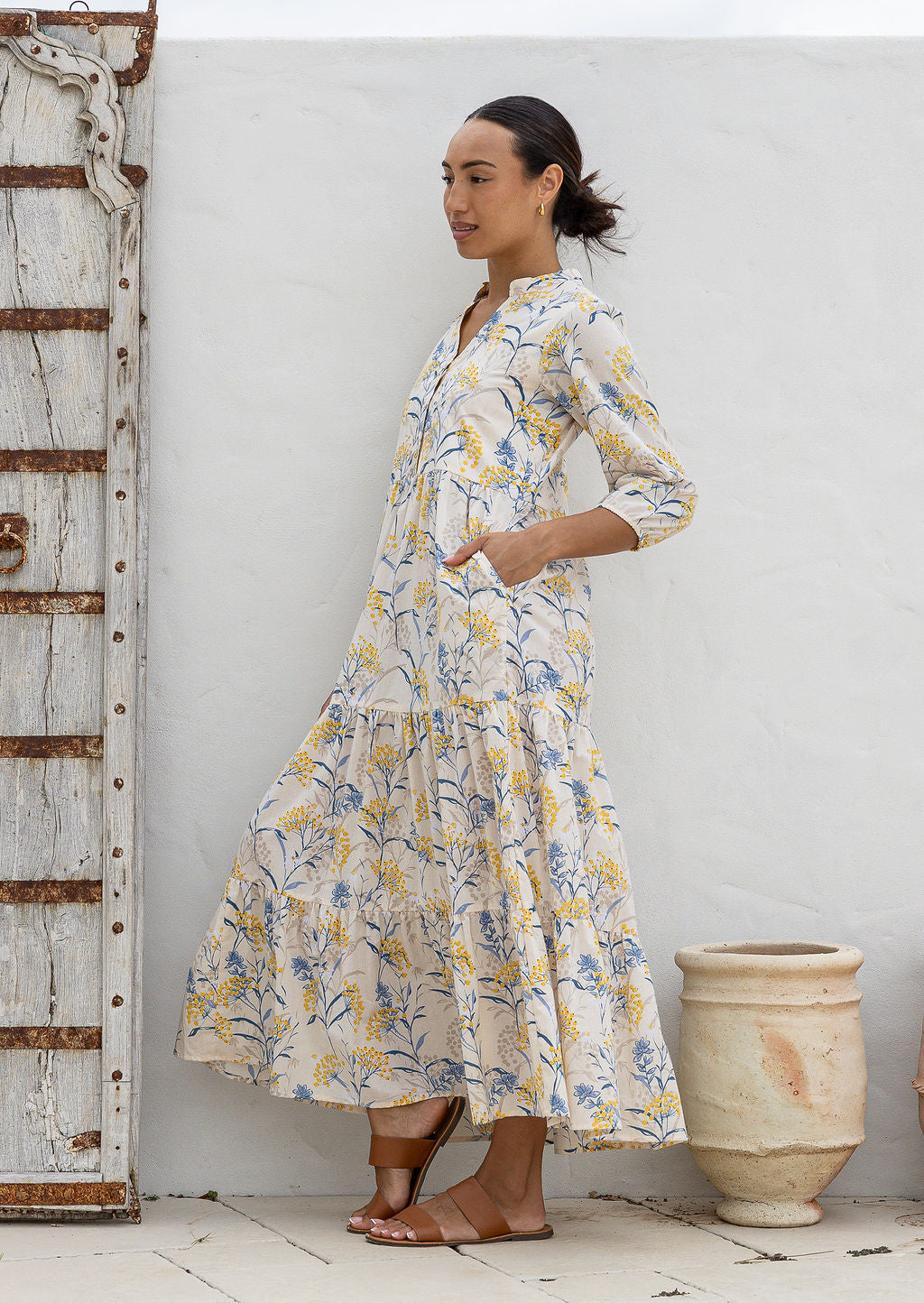 Woman standing in neutral based 100% cotton flowy tiered maxi dress with 3/4 sleeves, buttoned bodice and pockets