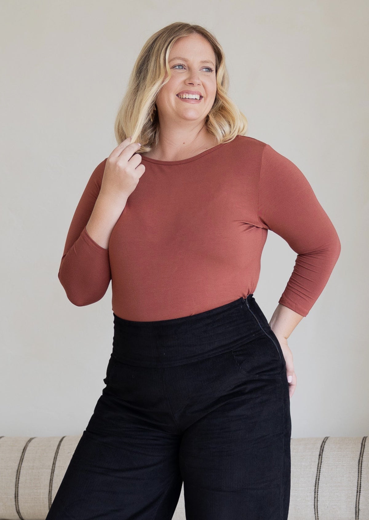 Woman wearing a rayon boat neck terracotta pink 3/4 sleeve top.