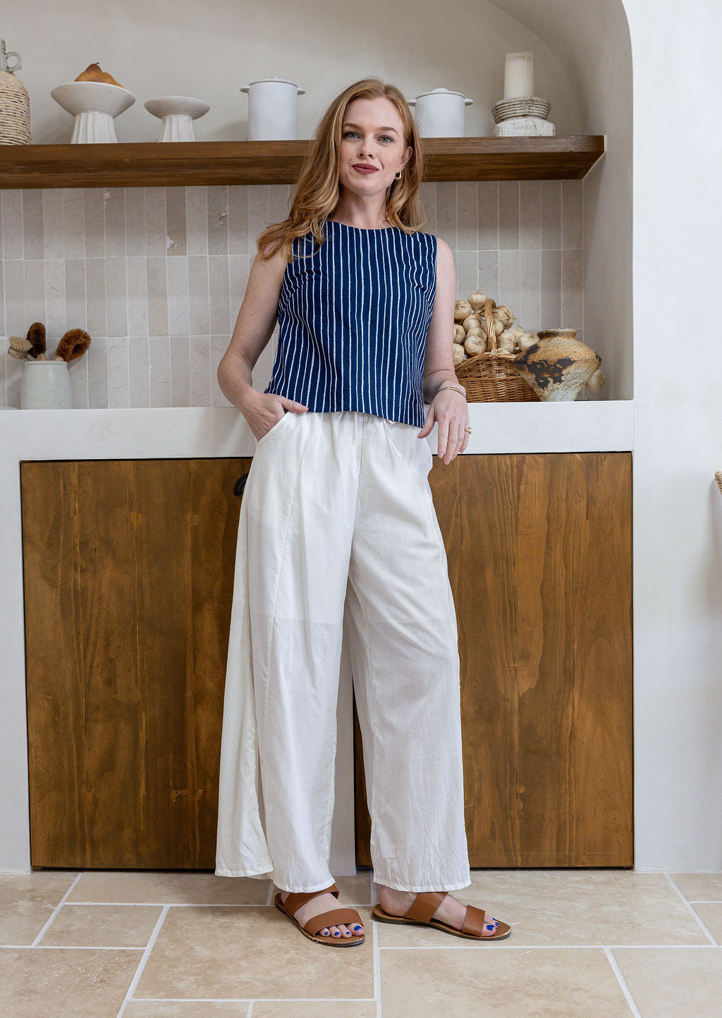 Model stands in white plain pants and relaxed fit floral print top with round neckline