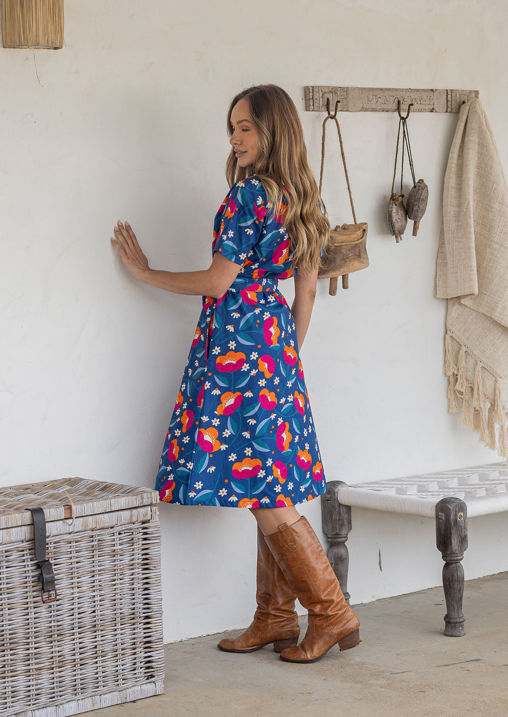 Model stands sideways wears 1950s inspired, button through shirt style dress with collar, short sleeves, waist tie and pockets.