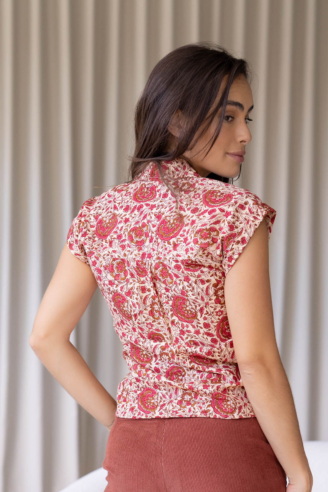 woman standing backwards wearing a gentle cream based floral printed slim fit shirt against a white background.