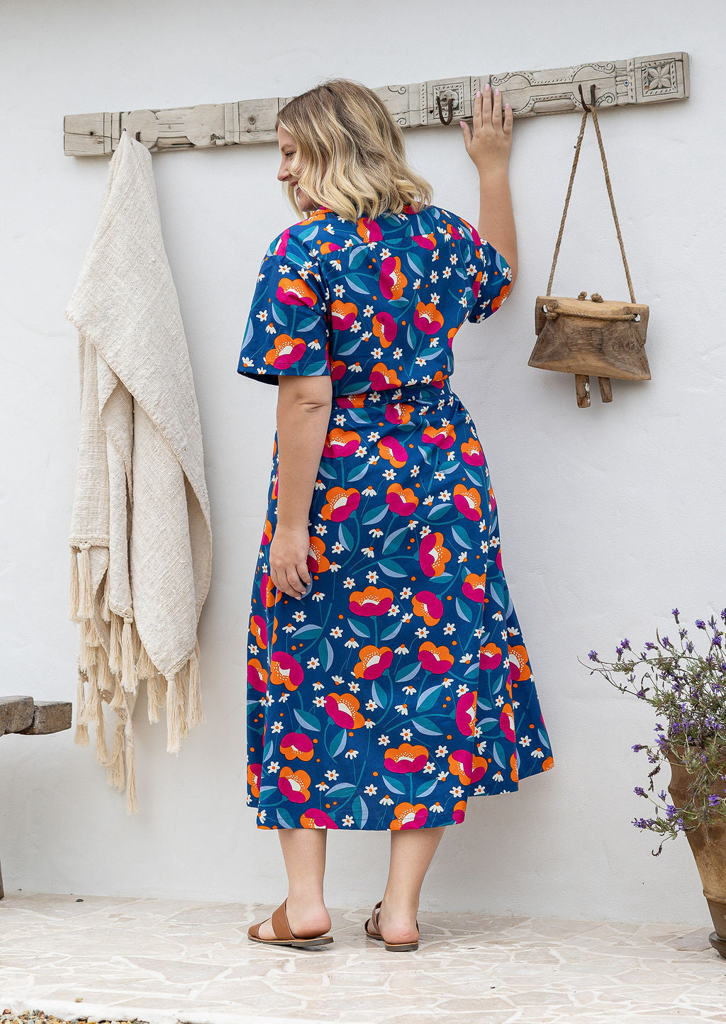 Model standing backwards wearing a floral printed shirt dress with detachable fabric belt and short sleeves