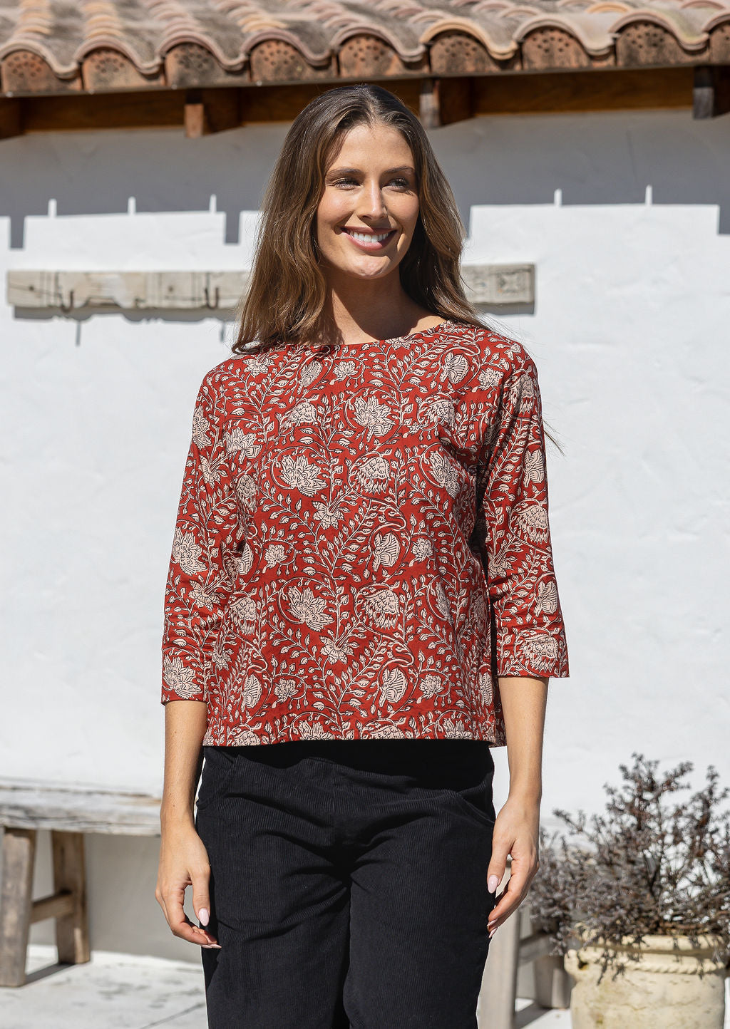 Model wears loose fit cotton top in red based floral print with black pants