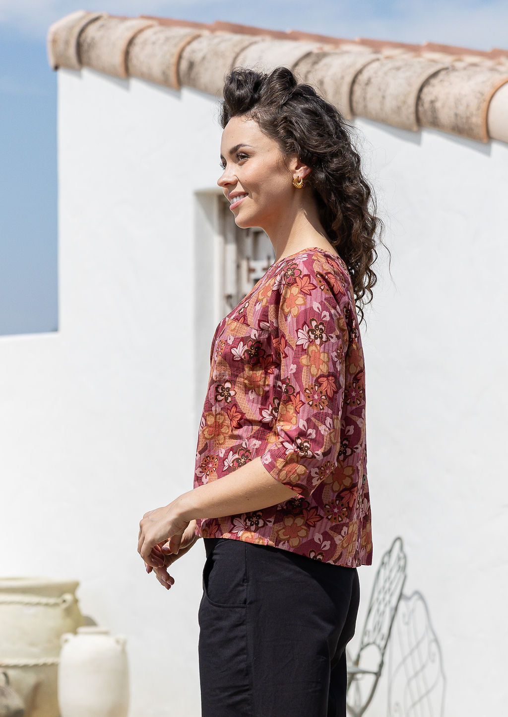 Woman stands sideways wearing relaxed fit, 100% cotton top in with loose 3/4 sleeves and wide round neckline.