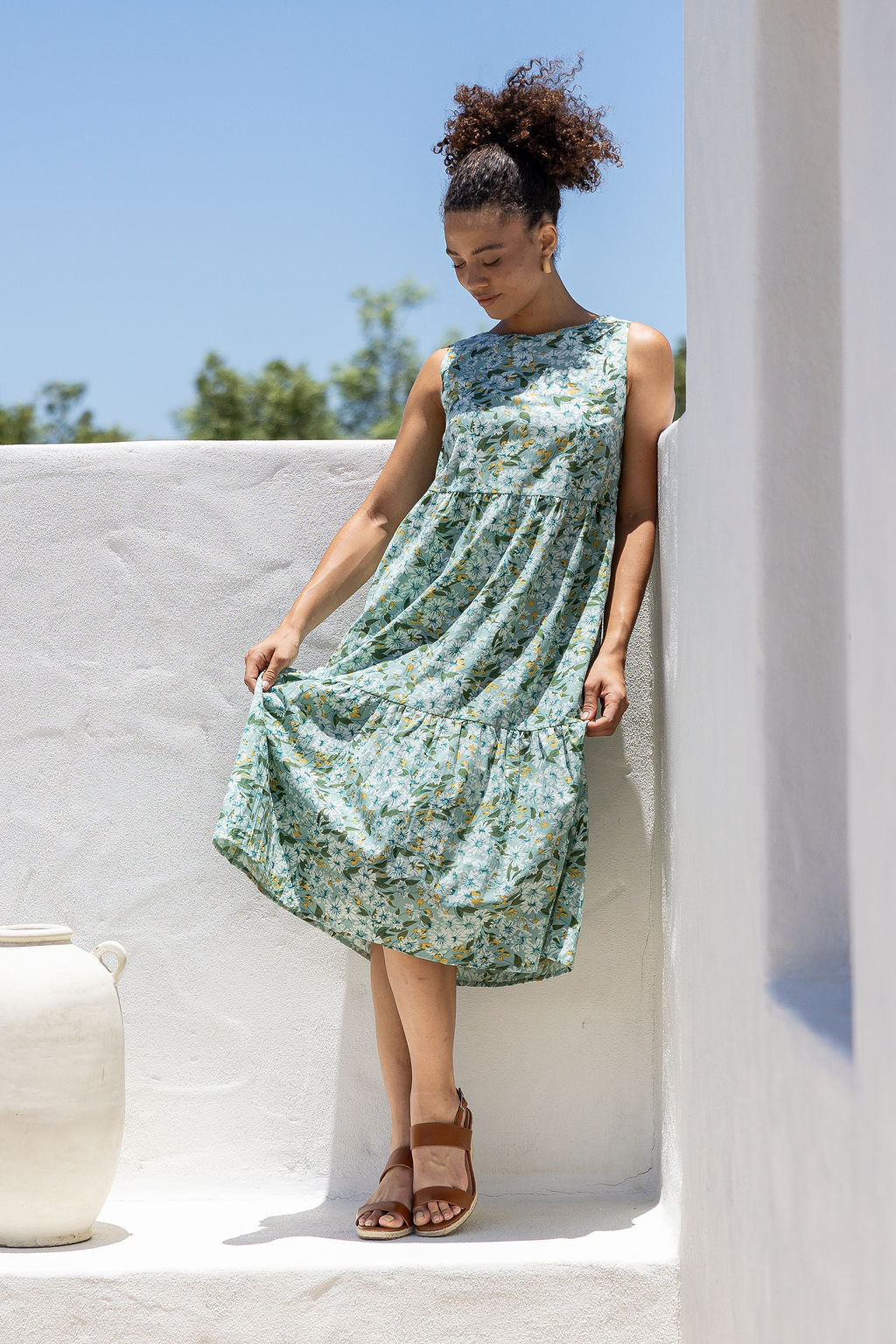 Model wears 100% cotton sleeveless midi dress with high round neckline, tiered design and pockets in sage green based floral print