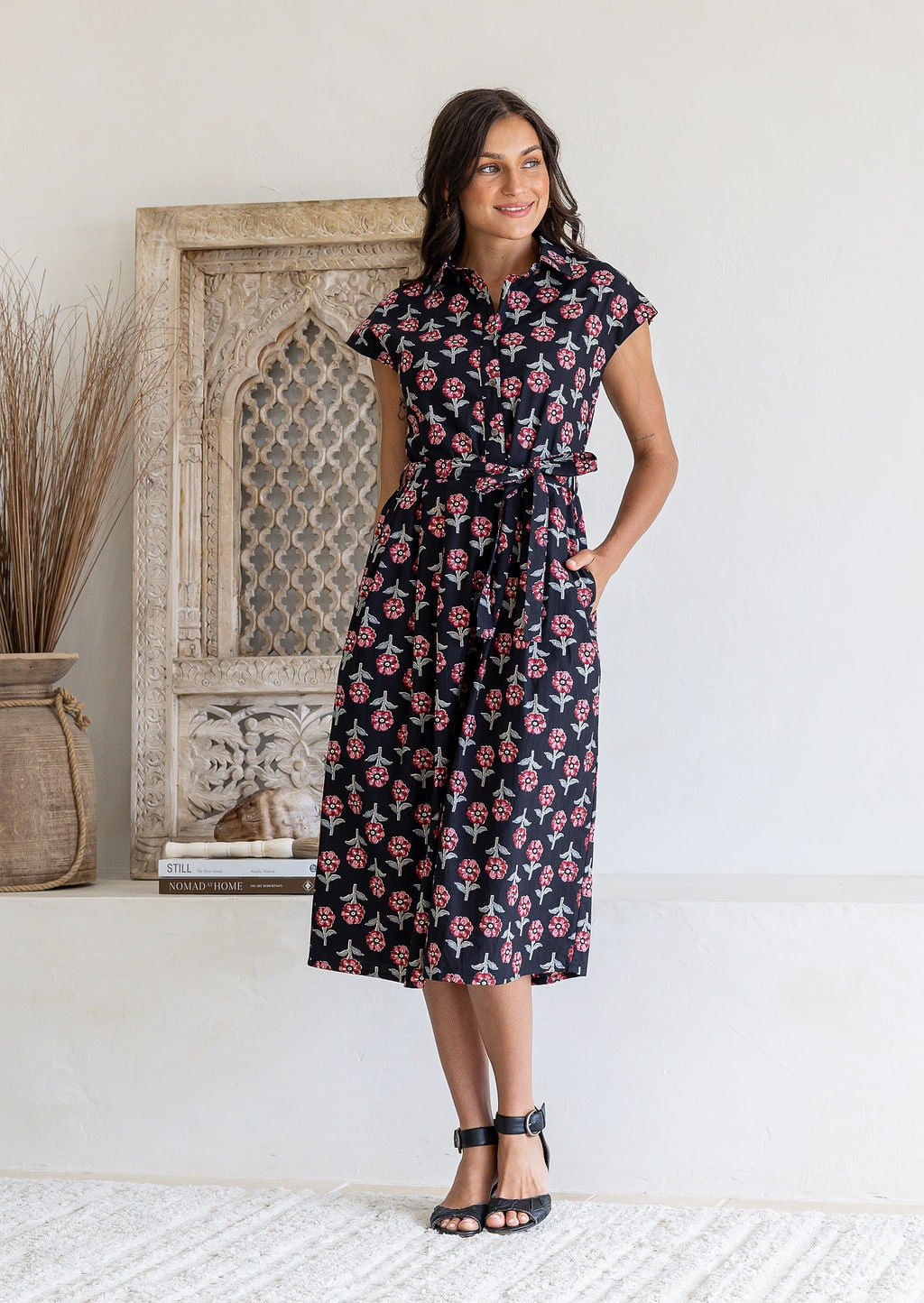 Woman posing in a 100% cotton Black floral midi shirt dress with cap sleeves and tie waist.