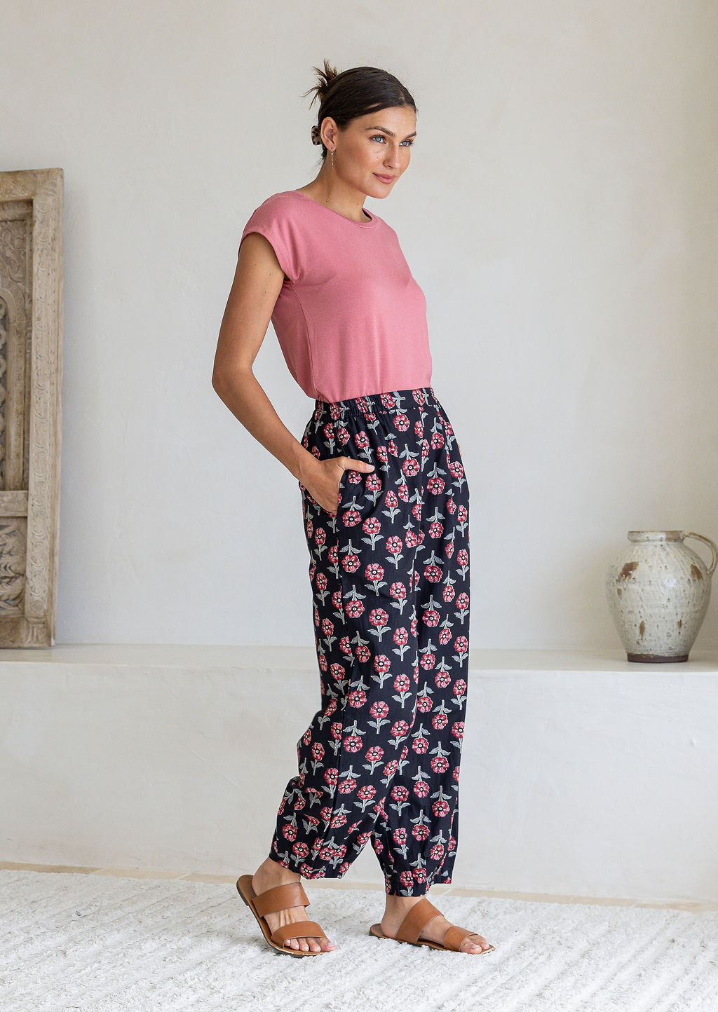 Model stands sideways wearing a 100% cotton printed wide leg cotton pants featuring pleated ankles and pockets.