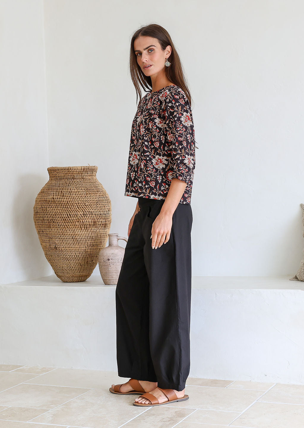 Woman stands sideways wearing relaxed fit, 100% cotton top in with loose 3/4 sleeves and wide round neckline.