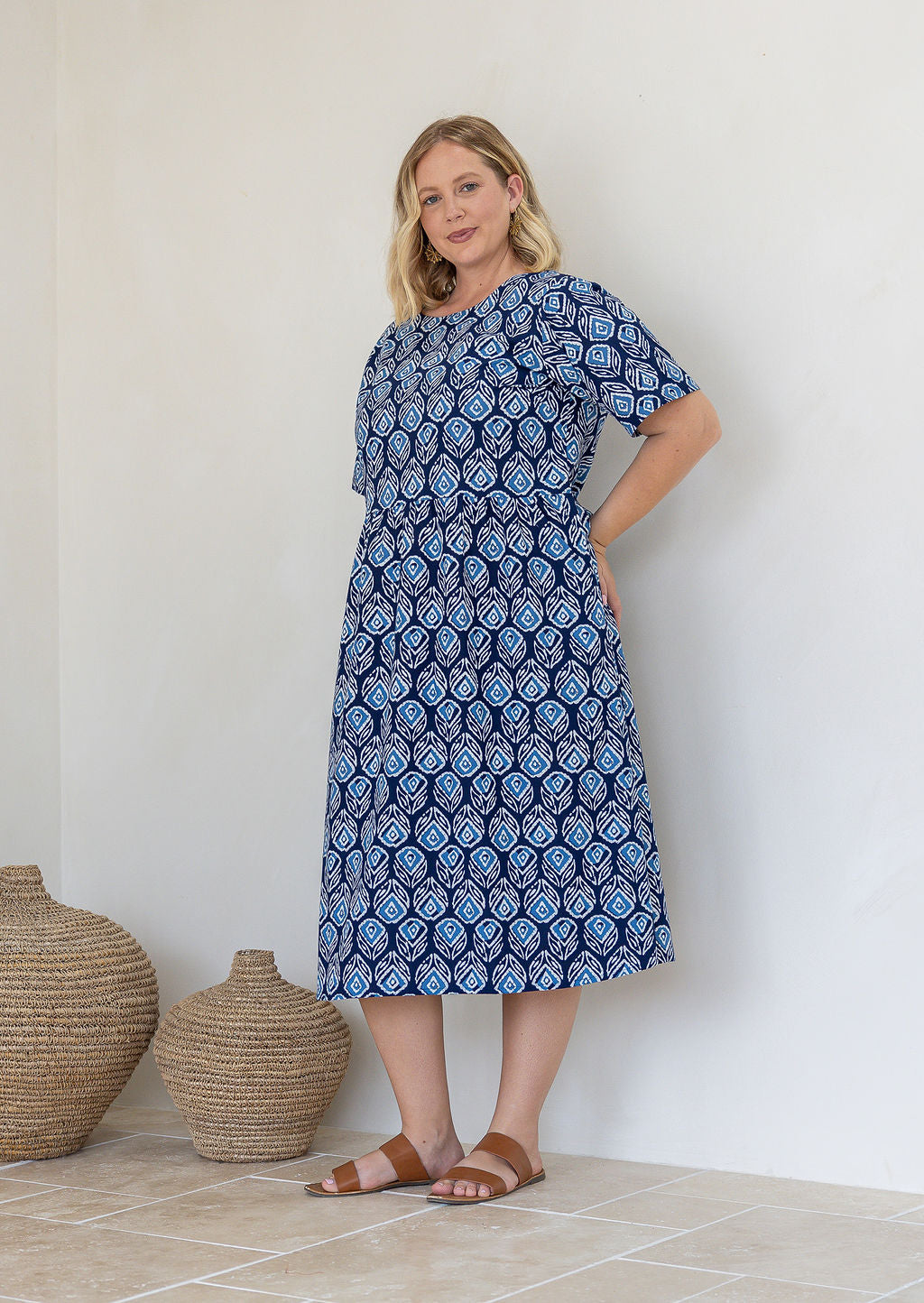 Woman wearing a 100% cotton relaxed fit dress in navy based floral print with round neckline