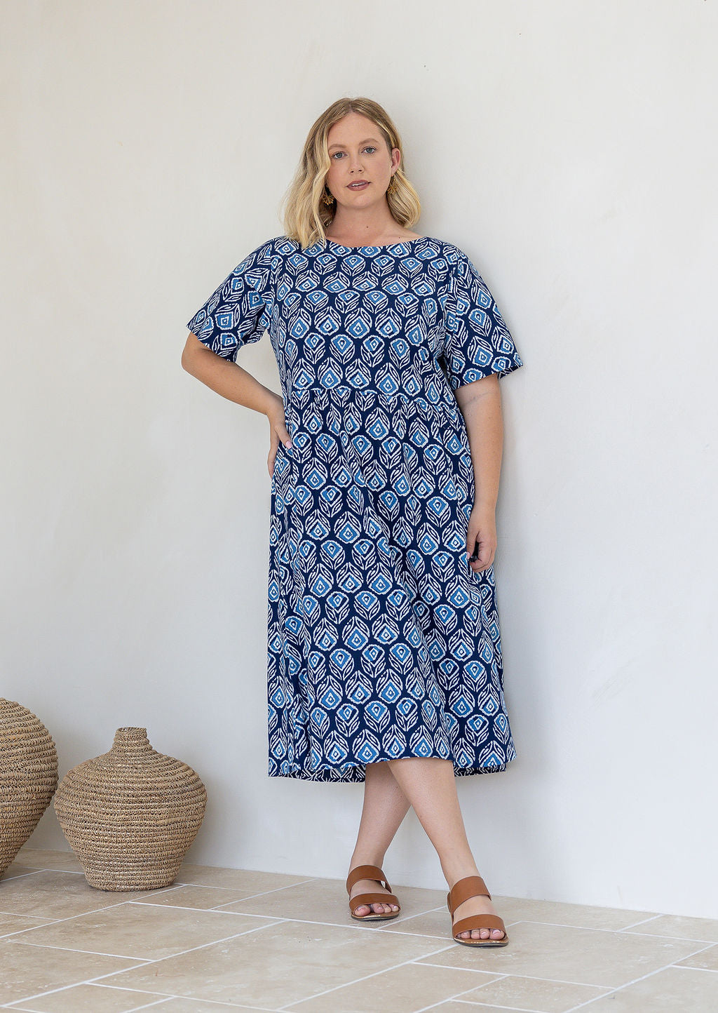 Woman wearing a 100% cotton relaxed fit dress in navy based floral print with round neckline.