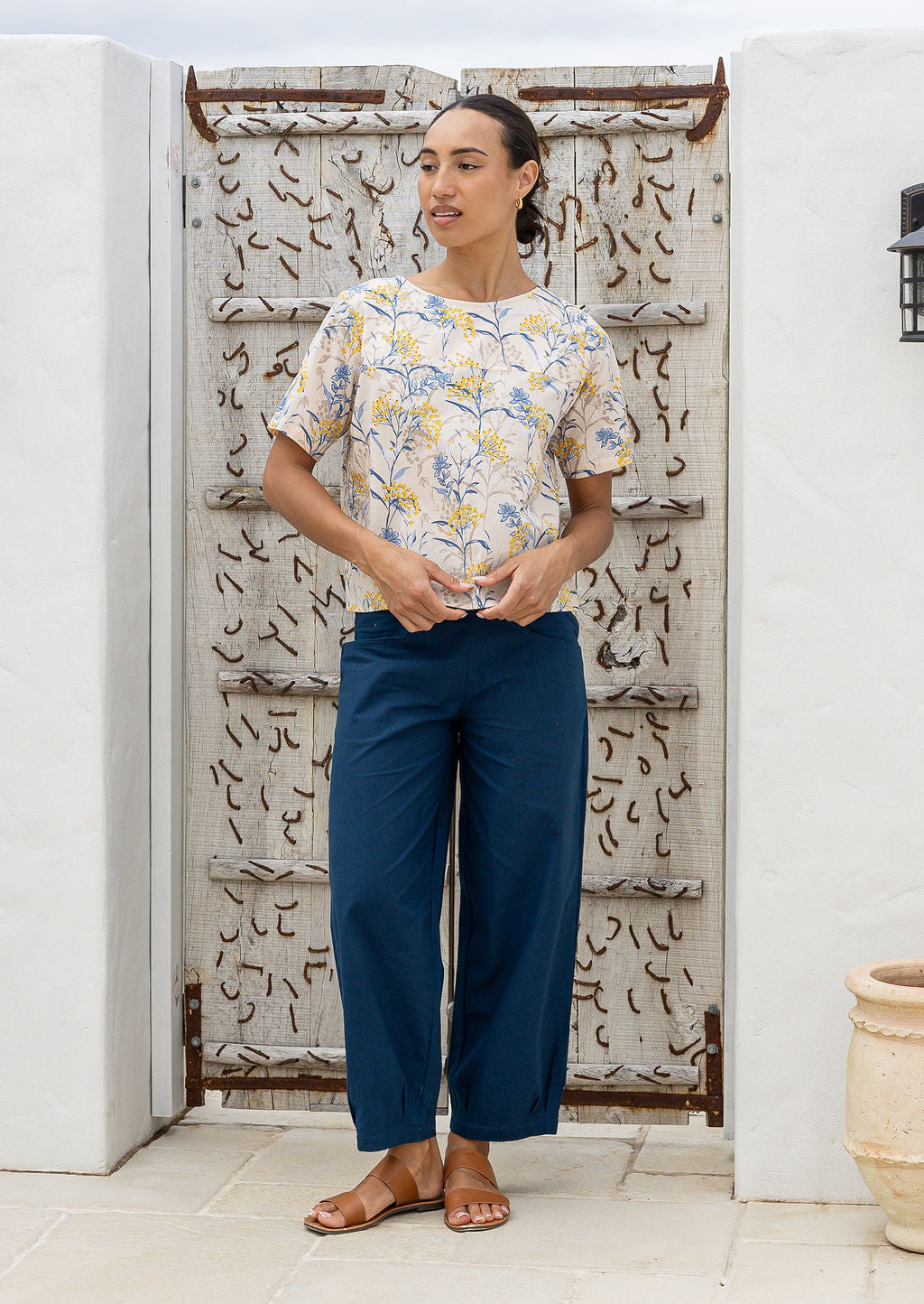 Woman posing in a 100 percent cotton loose cut blouse in neutral based floral print and plain blue pant.