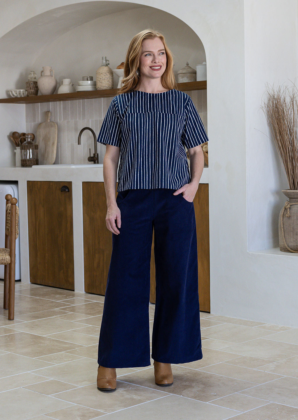 Woman wearing a navy blue and white striped short sleeved cotton top and navy pants.