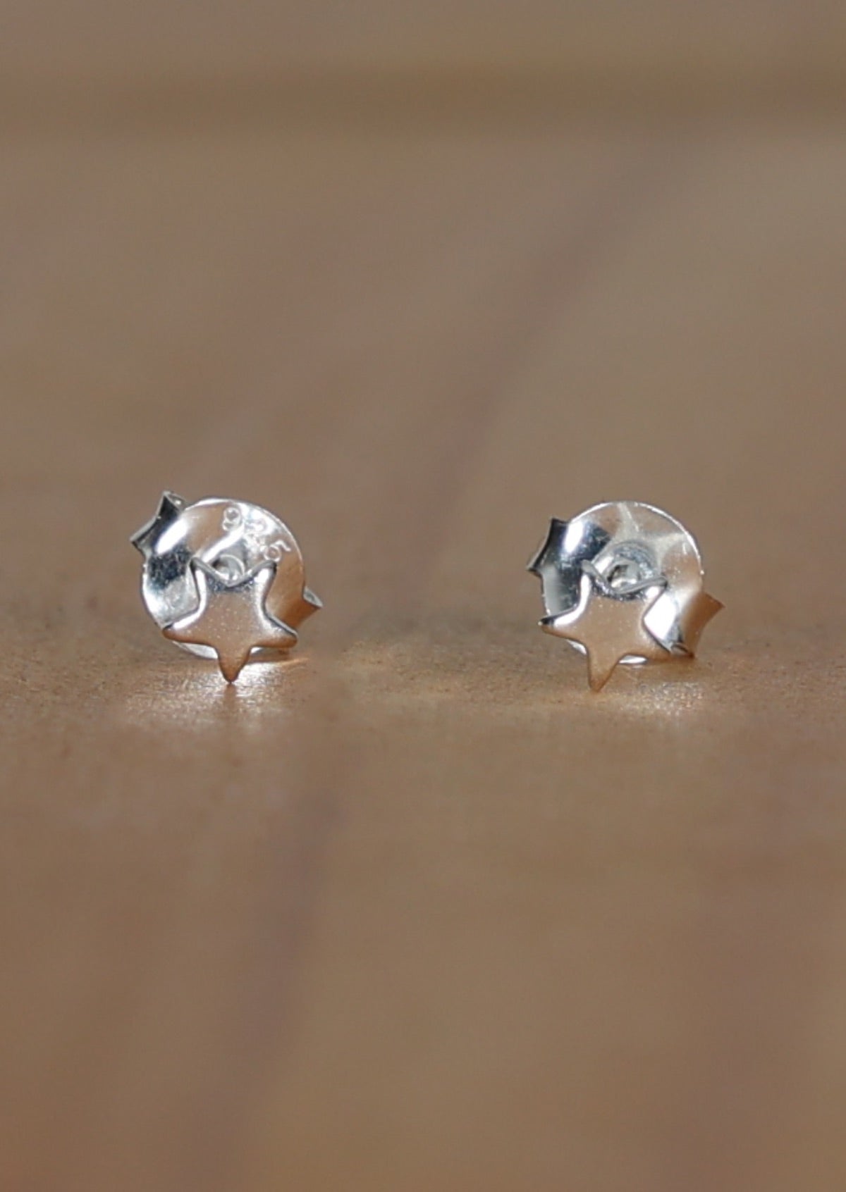A pair of sterling silver star-shaped stud earrings laid on a wooden surface