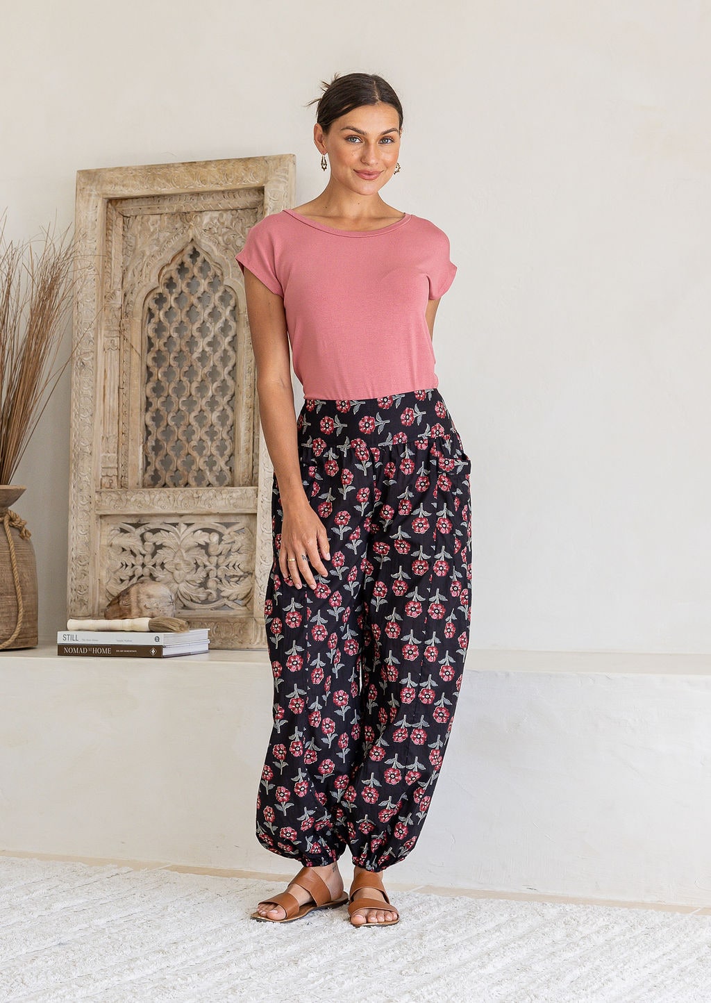 Woman wearing a basic pink t-shirt and black floral print harem pants.