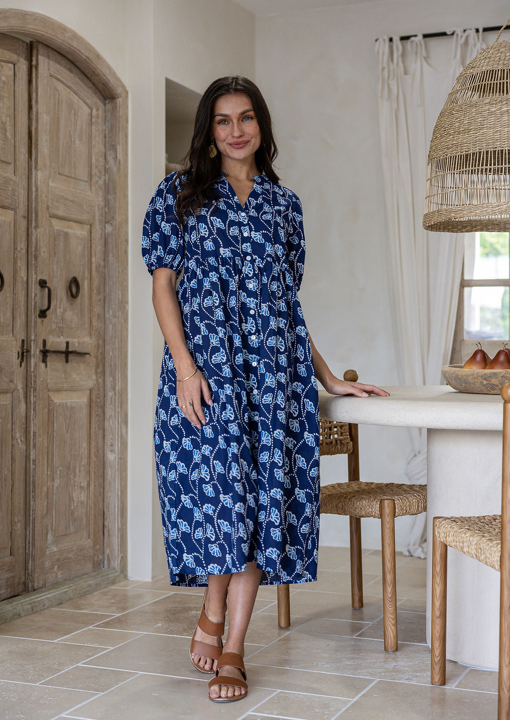 Woman wearing navy based colourful floral cotton button through dress with side pockets