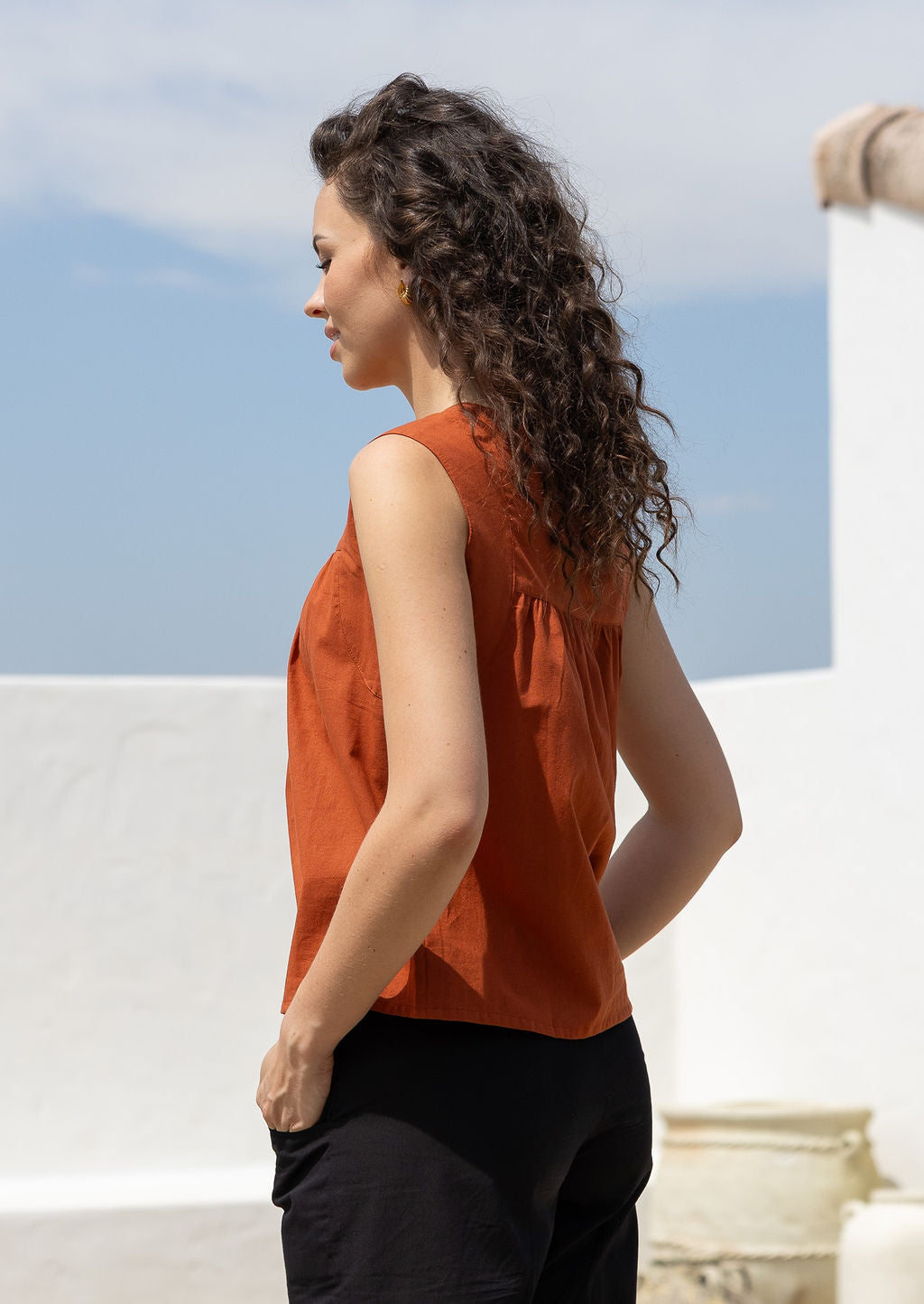 Woman wears cotton top with small gathers under the neckline yoke, both front and back, that gives this top a loose fit
