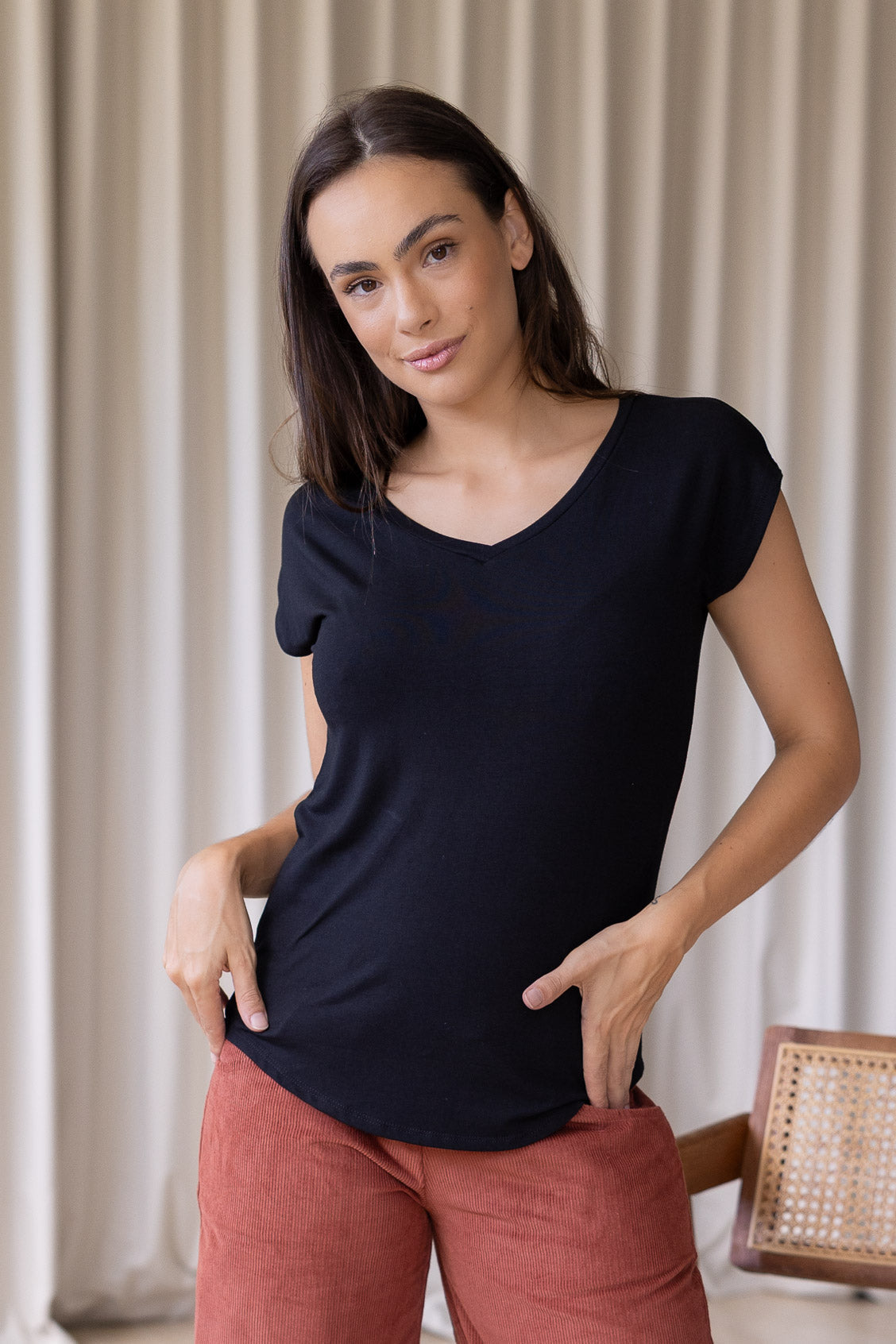 Woman wearing a black rayon jersey t-shirt with a V-neck and cap sleeves