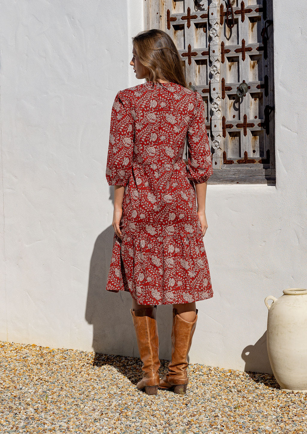 Model stands backwards in cotton over the knee length relaxed fit dress with 3/4 sleeves, paired with brown boots.