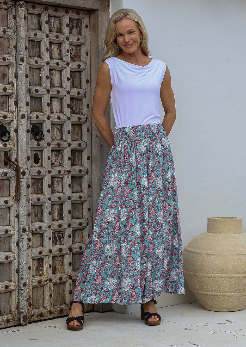 Woman wearing a basic white rayon top paired with duck egg blue based floral print super wide leg pants with a smocked elastic waistband.