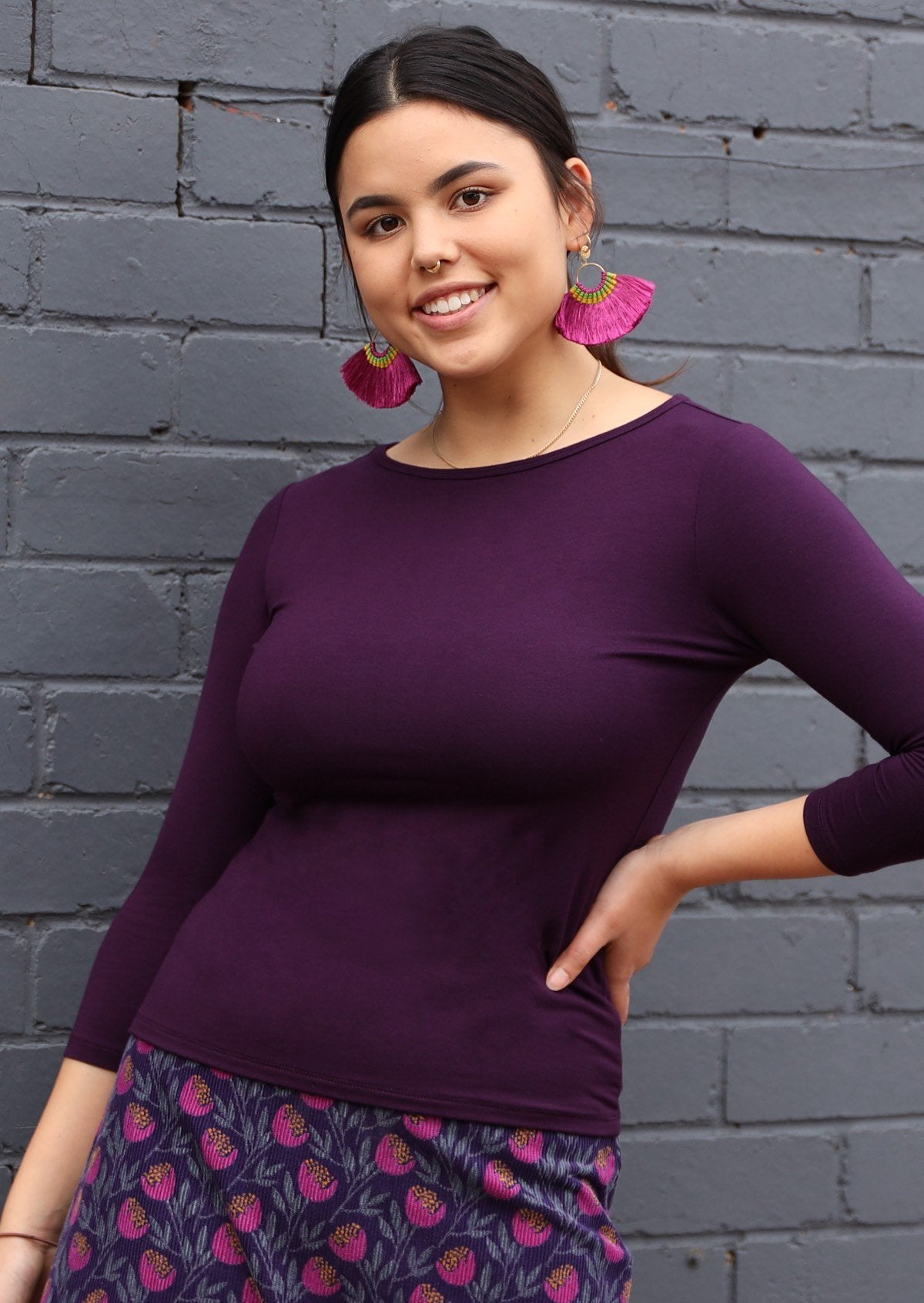 Woman wearing a rayon boat neck purple 3/4 sleeve top.