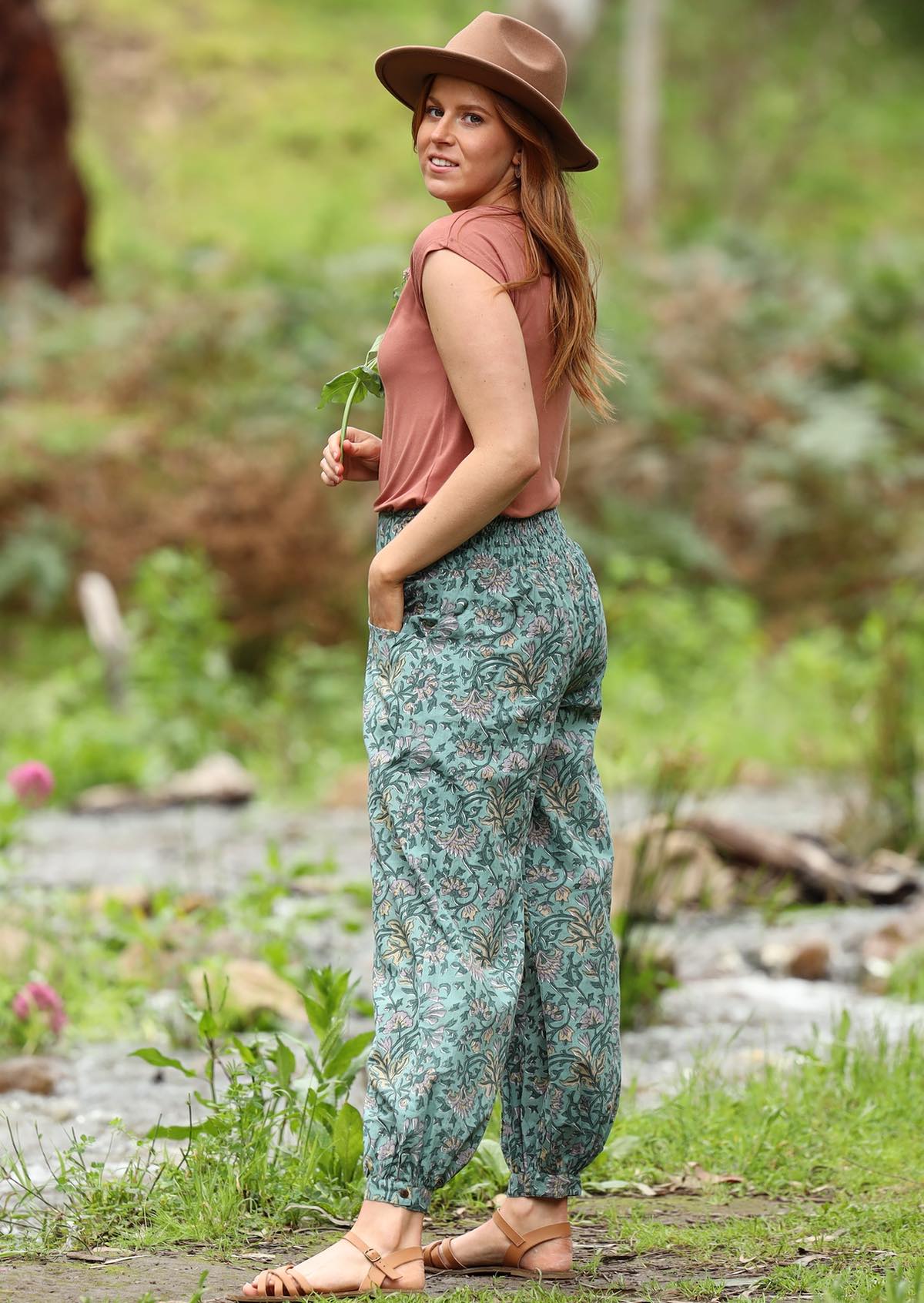 Model wears Light weight cotton women's floral printed pants with hand in pocket.