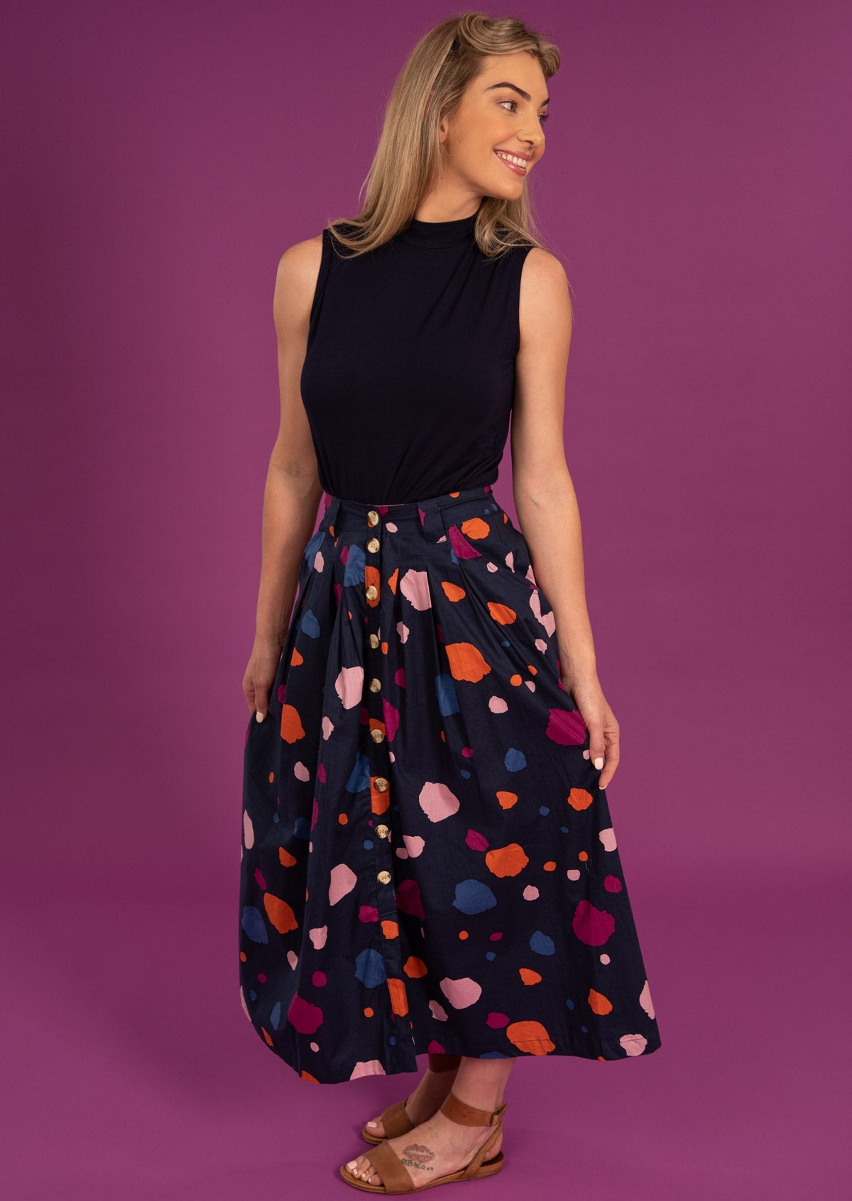 Woman wears cotton button through skirt with Box pleats and pockets.